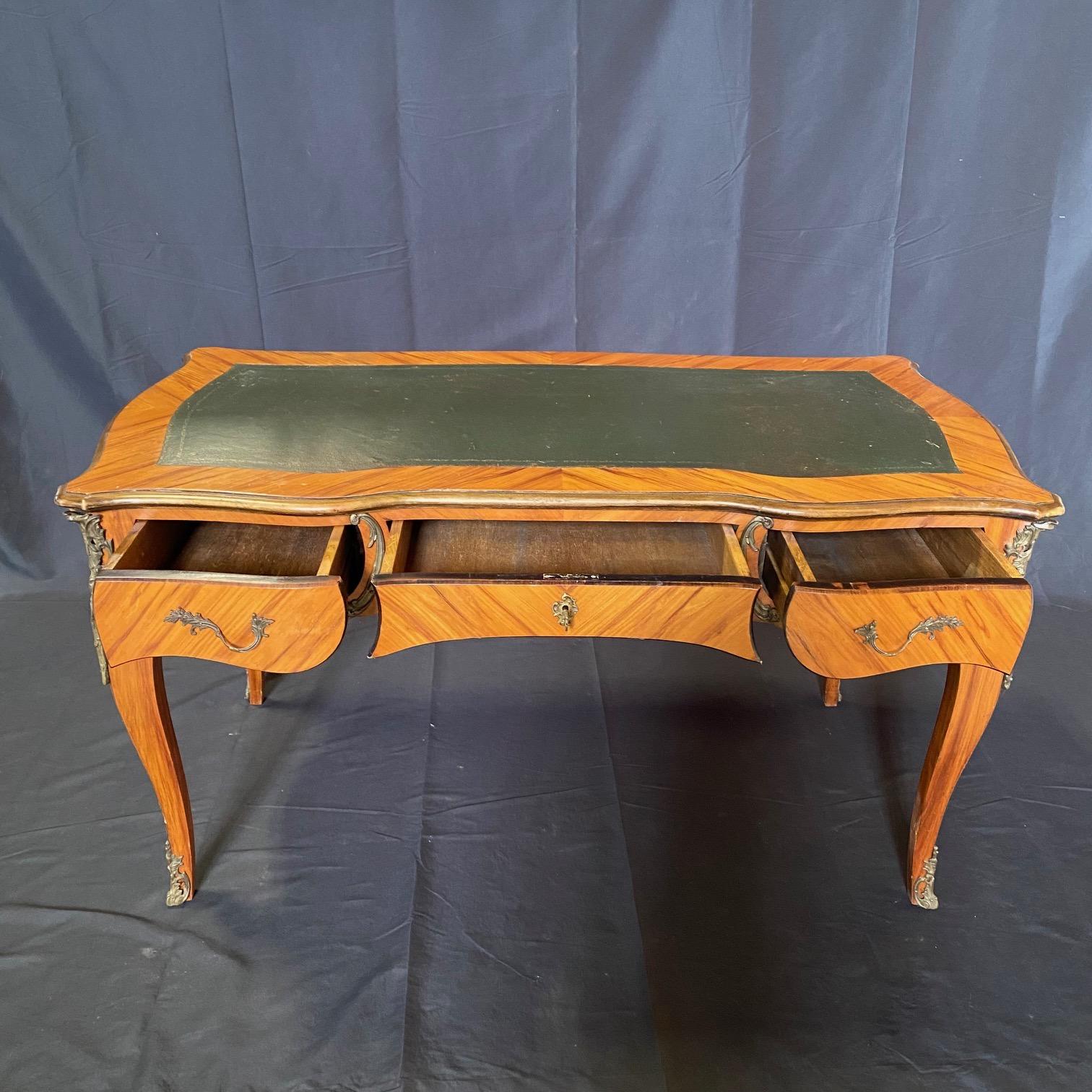 An outstanding French Louis XV desk having embossed leather top and a faux front on its back so will look lovely in the center of any room. The writing desk has three spacious drawers, and is raised on cabriole legs with floral gilt bronze cast