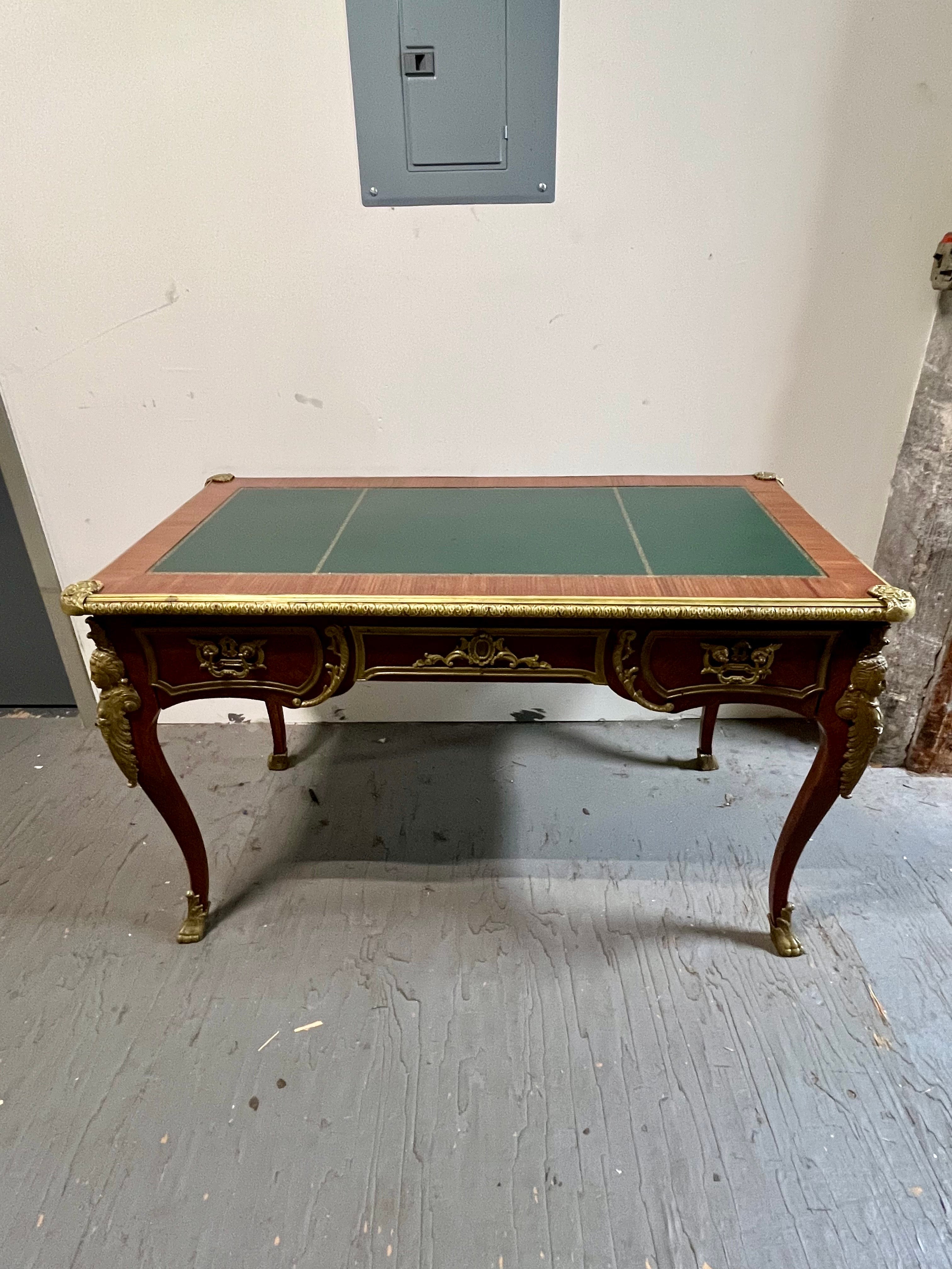 A gorgeous French Louis XV style executive writing desk or bureau plat desk

Mahogany, with bronze/bronze trim and ormolu mounts, and embossed green leather top. Remnants of gilt finish.

Measures: 48.5