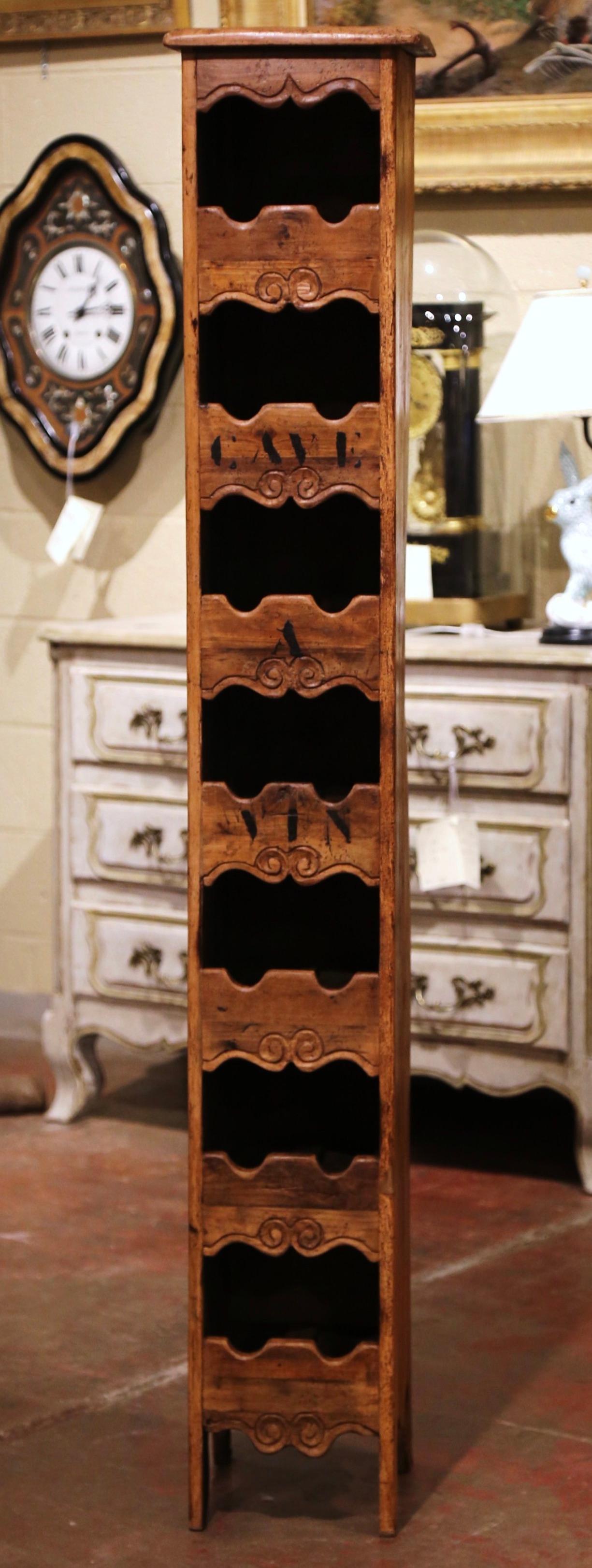 This narrow, antique wine cabinet was crafted in western France using old timber. The tall, thin, simple pine cabinet sits on small scroll feet under a scalloped apron. The display piece with the words “Cave a Vin” printed on the front (which