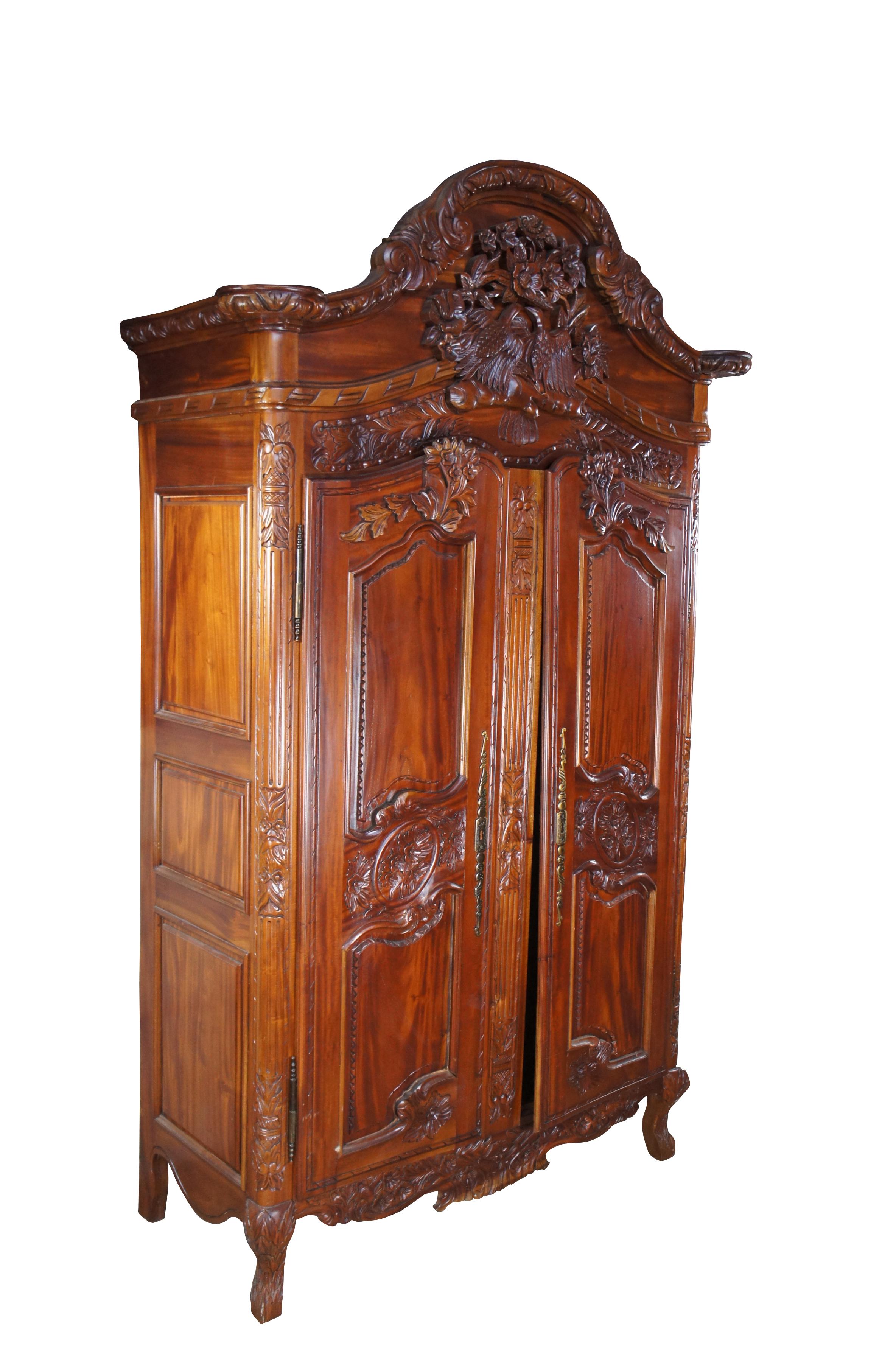 Vintage French Louis XV / Provincial style wedding armoire or wardrobe, circa last quarter of the 20th century. Made of mahogany featuring baroque styling with a foliate carved bonnet top crown over a floral bird theme.  The armoire has paneled
