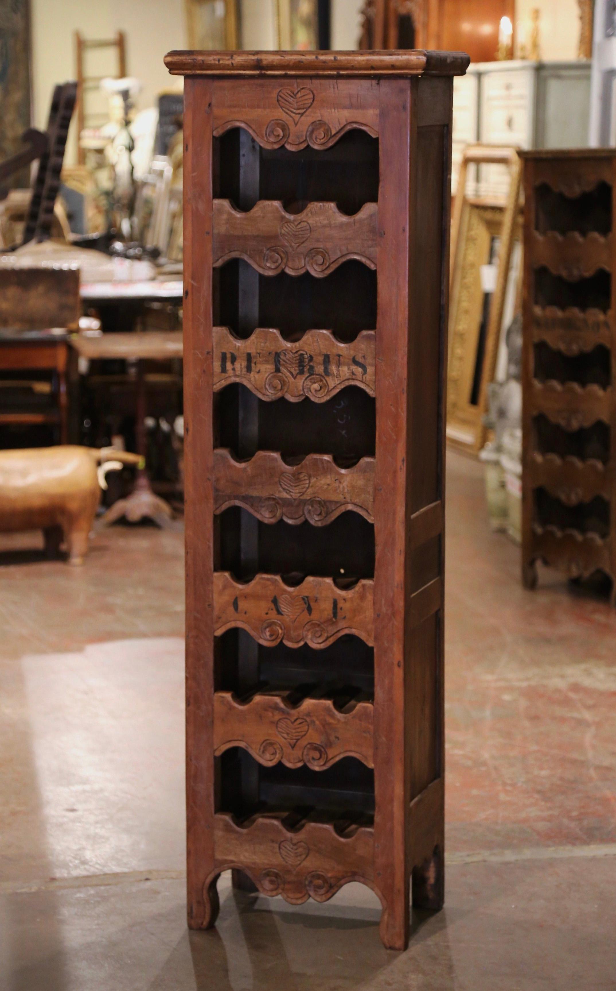 This narrow, antique wine storage cabinet was crafted in western France using old timber. Built of pine wood, the tall and thin cabinet sits on four small scroll feet under a scalloped apron.  The piece features six shelves embellished with