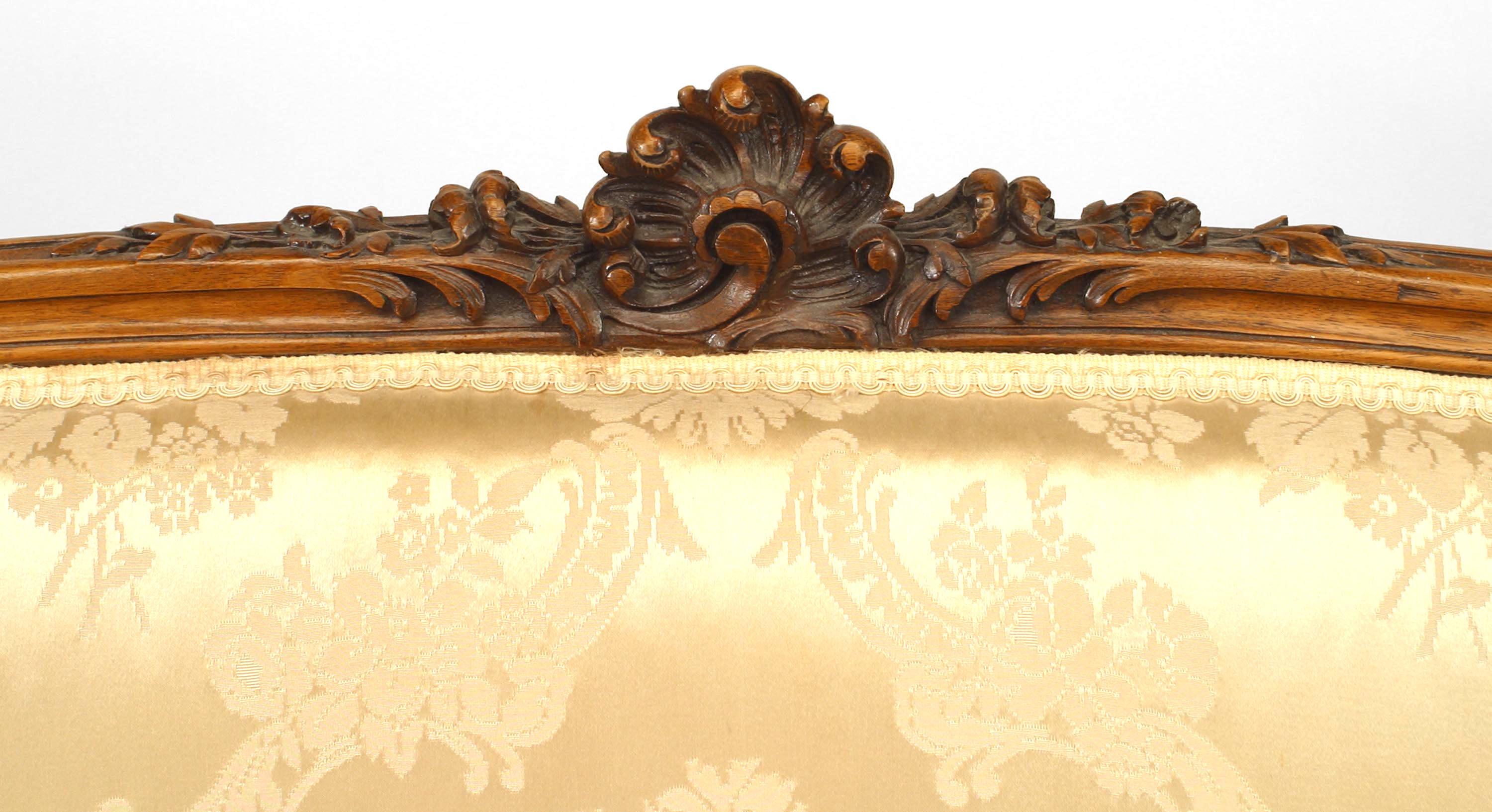 Causeuse en noyer de style Louis XV (20ème siècle), tapisserie en brocart blanc cassé et dossier sculpté.

Une jambe n'est pas porteuse de poids.