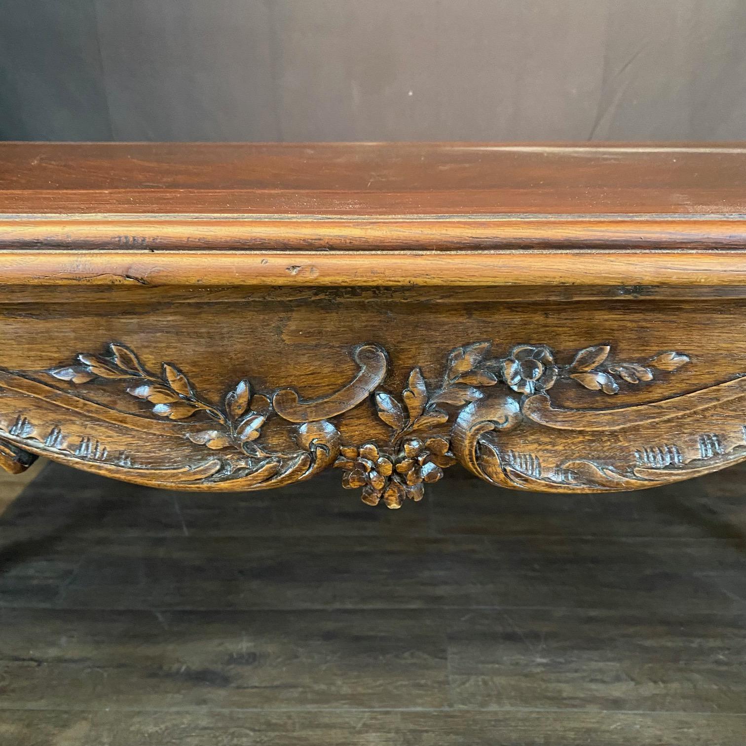 Antique French Louis XV dining table with exquisite carving on all sides. Hand-crafted from solid walnut, the table top is book matched veneer with border, and is supported by a lovely apron carved all around with shell and foliate motifs, in turn