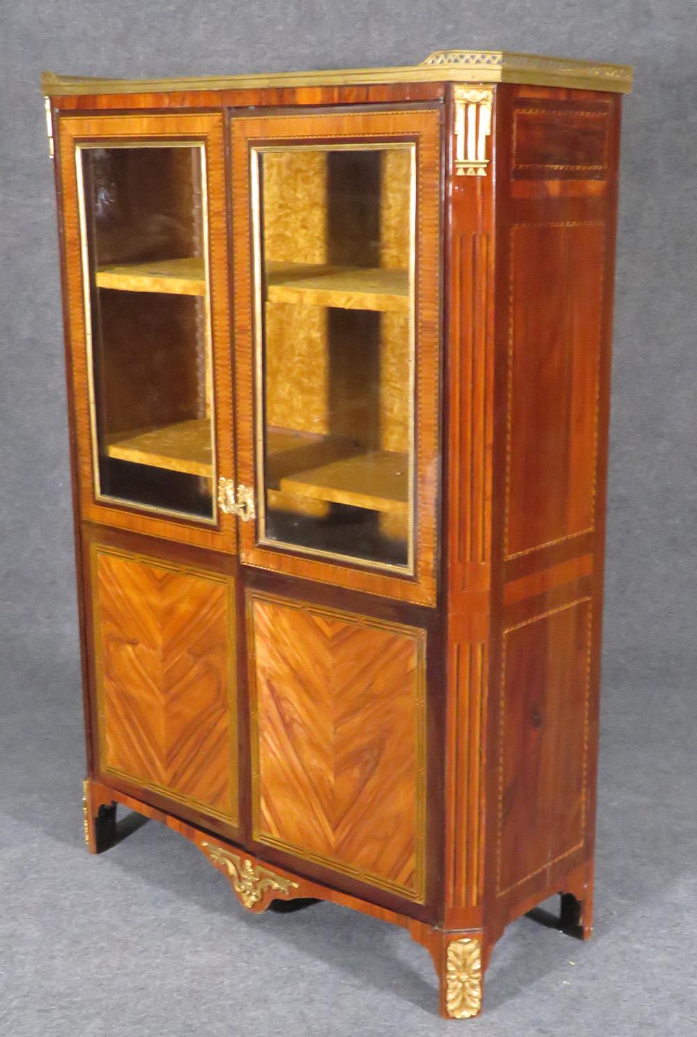 This is an 1890s French gilded bronze bookcase. The bookcase features incredible Kingwood and walnut construction and a marble top. The bookcase is in original condition with age checking which we can touch up, but will probably never be entirely
