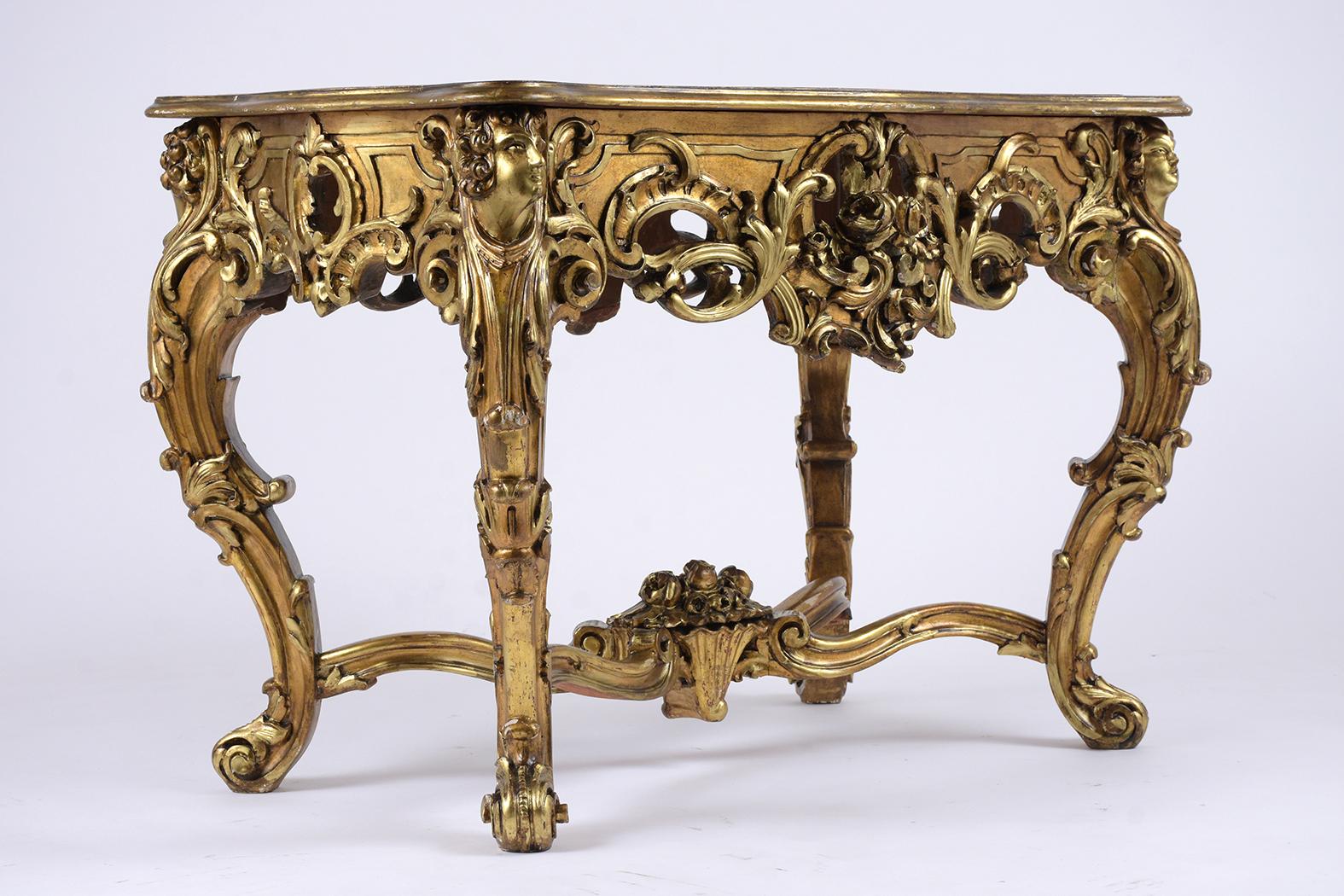 This French antique Louis XV giltwood carved center table features an original insert marble top a finely carved through ou the entire piece cabriole legs detail and has an X-shaped stretcher with a large basket flower in the center.