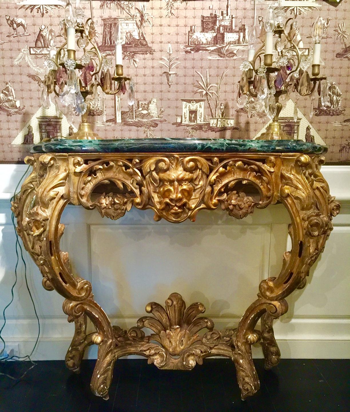 French Louis XV giltwood console, 18th century, green marble top
Rococo style with mascaron lion frieze, ornately sculpted, feathers joining the elegant legs. A beautiful model. Thick green marble top with white veins.

The gilding has been