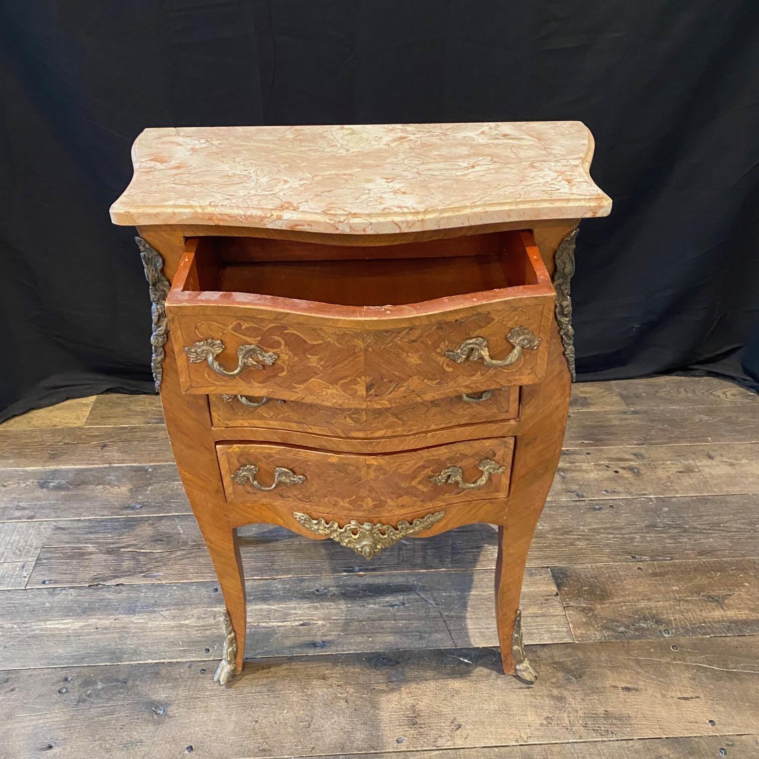 A petite Louis XV period serpentine commode with shaped front and having original shaped marble beveled top mounted with a lovely mottled beige marble top, gilt-bronze mounts and hardware throughout, three drawers and ending in gorgeous bronze