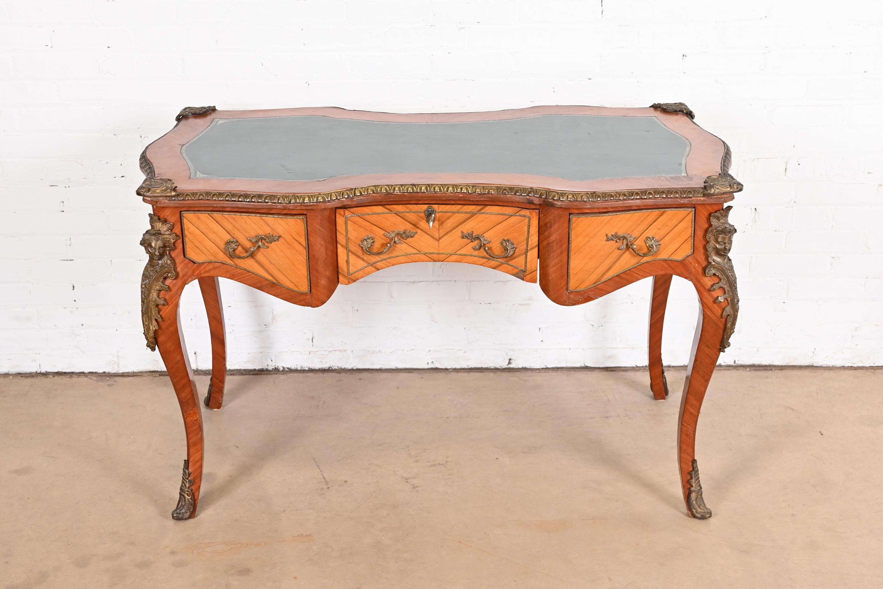 An outstanding French Louis XV style writing desk or bureau plat desk

France, Circa 1940s

Gorgeous kingwood, with bronze trim and ornate ormolu mounts, and embossed green leather top.

Measures: 52.5