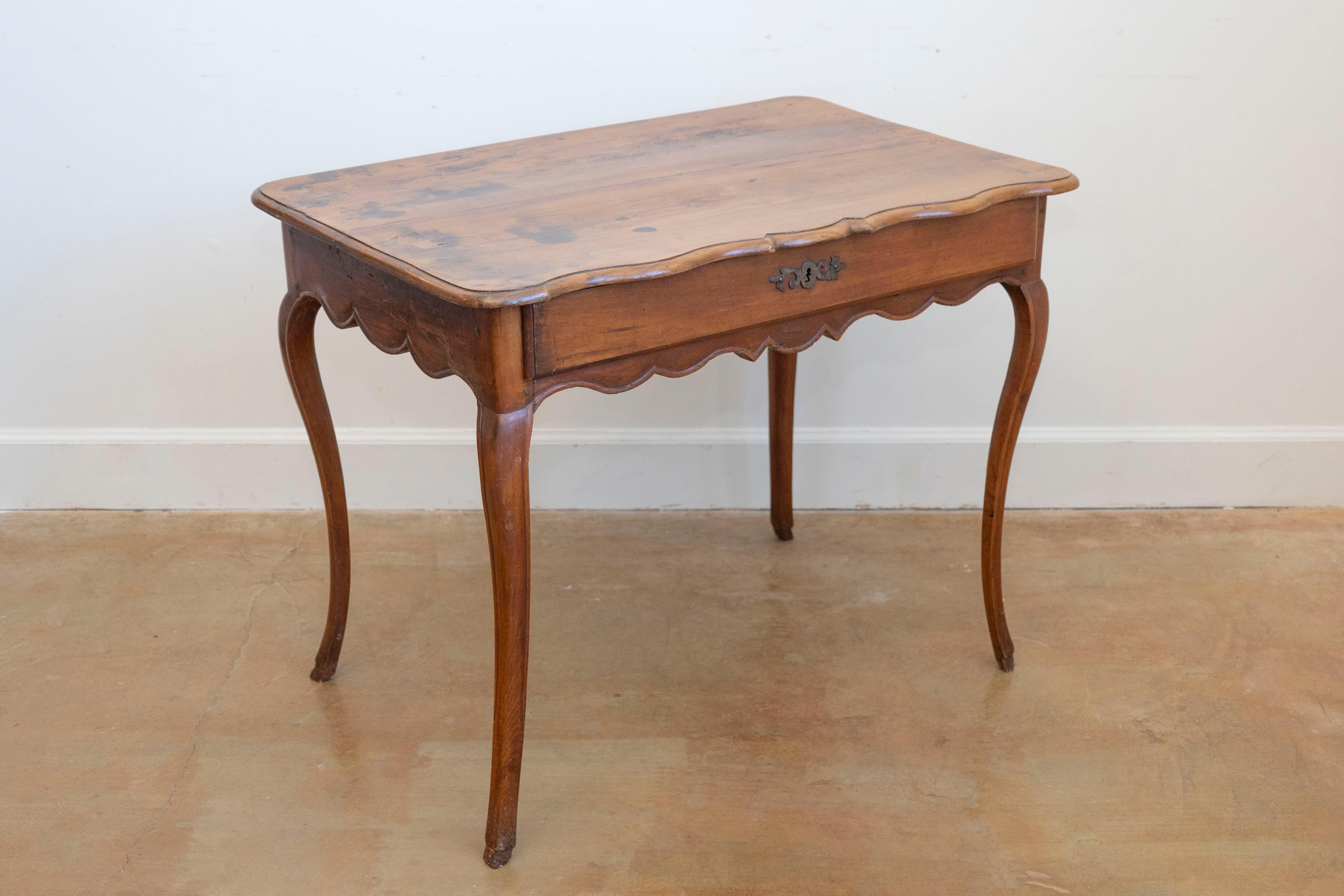 A French Louis XV cherry table from the Rhône Valley, with long drawer and cabriole legs. Born in France in the later years of the 18th century, this cherry table features a rectangular top with serpentine front, sitting above a long drawer. Raised