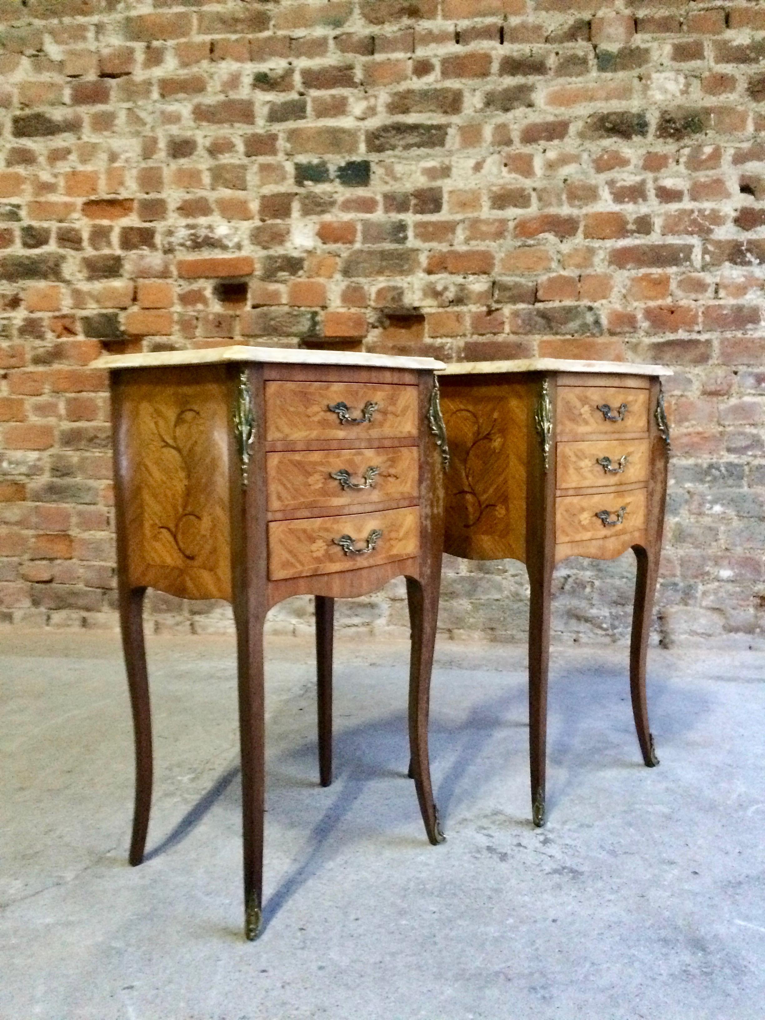 Antique French pair of Louis XV style marble topped Bombe Commode bedside cabinets dating to early 20th century, the scalloped cream marble tops over three drawers with dual bronze handles and gilt mounts, bronze accents to the sides and legs, all
