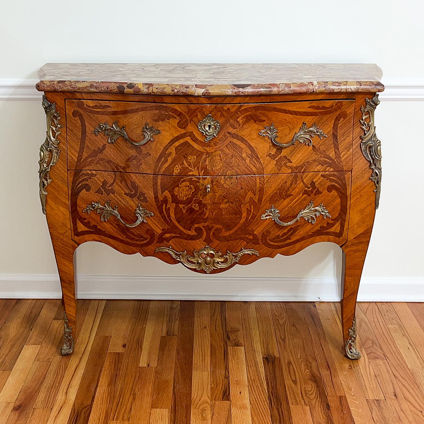 A fine French Louis XV marble top commode with serpentine and bombay form, this commode has Breche D'Alep marble with a molded edge, fine detailed floral marquetry patterns, rococo gilt bronze mounts, and sans traverse drawers. France, Late 19th