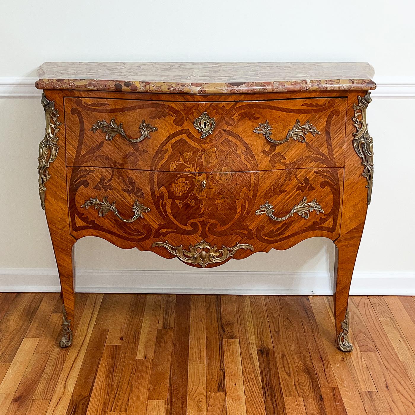 Questa bella commode francese con piano in marmo Luigi XV e forma a serpentina e bombay, presenta un marmo Breche D'Alep con bordo modanato, raffinati motivi floreali intarsiati, montature in bronzo dorato rococò e cassetti senza traverse. Francia,