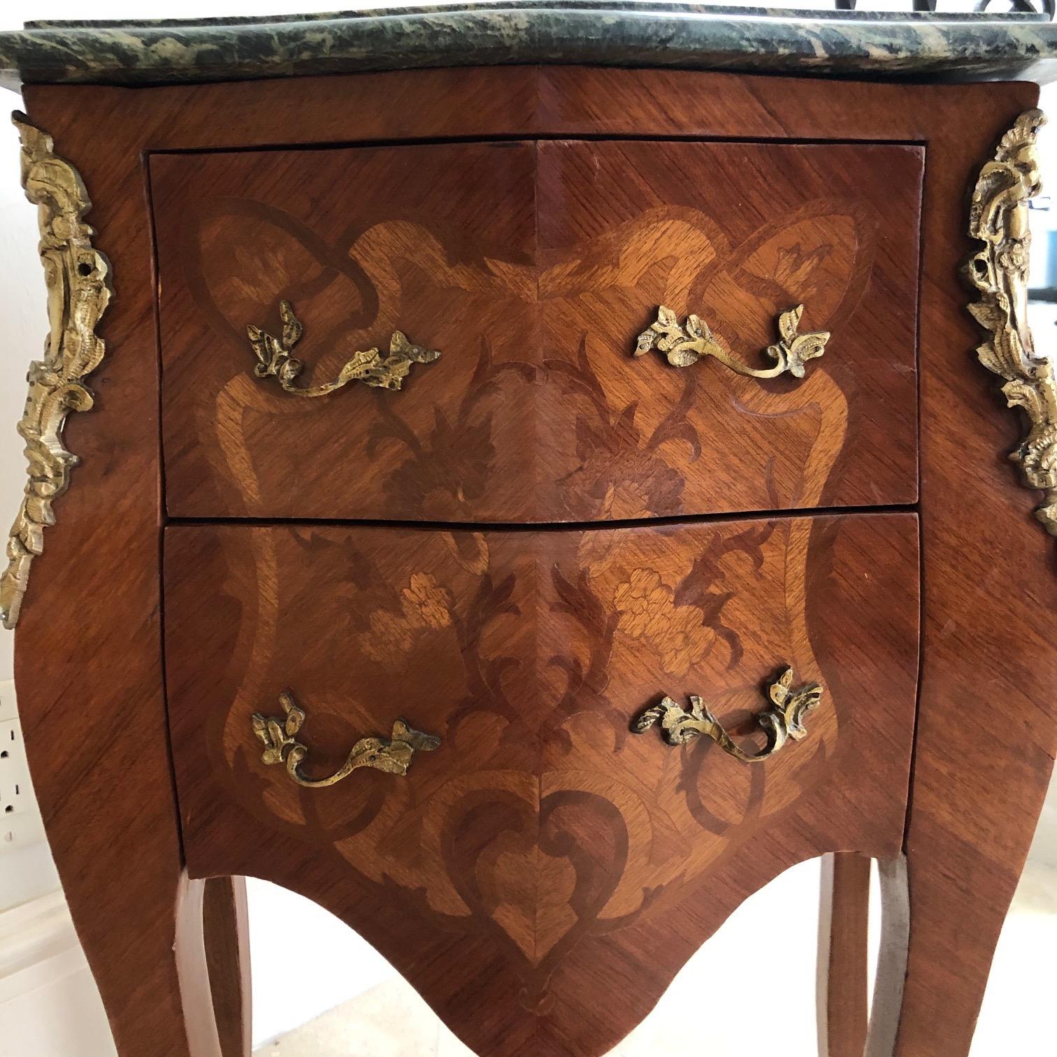 An exceptional Louis XV style mahogany nightstand or side end table commode. The
nightstand features gorgeous mahogany wood grain with inlaid marquetry and
a green beveled marble top. The nightstand offer two drawers, and the cases
rest on tall