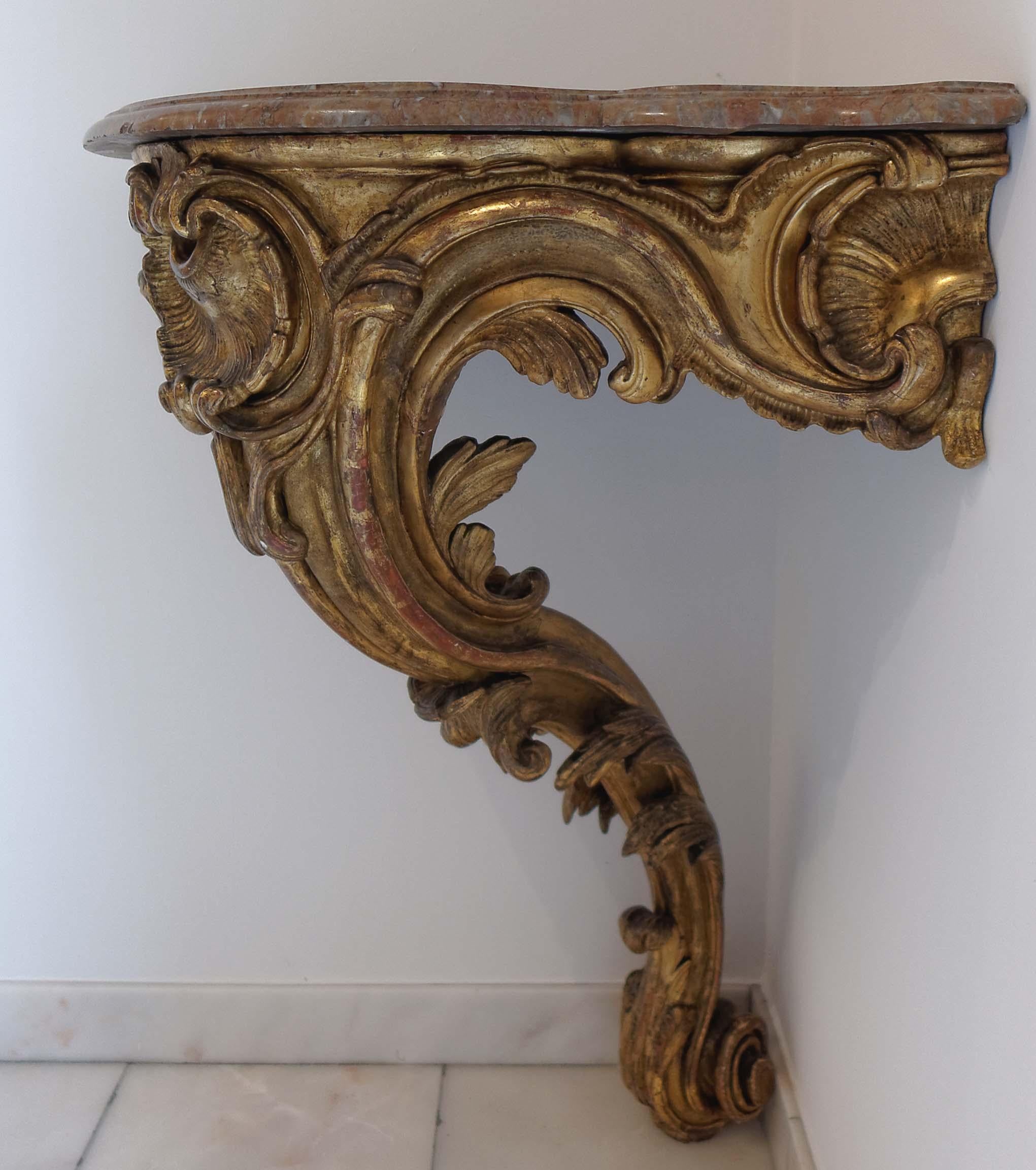 A very fine French Louis XV mid-18th century giltwood corner console table. Carved throughout with C-scrolls and foliage on a central leg terminating in a scrolling foot. Original moulded marble-top.