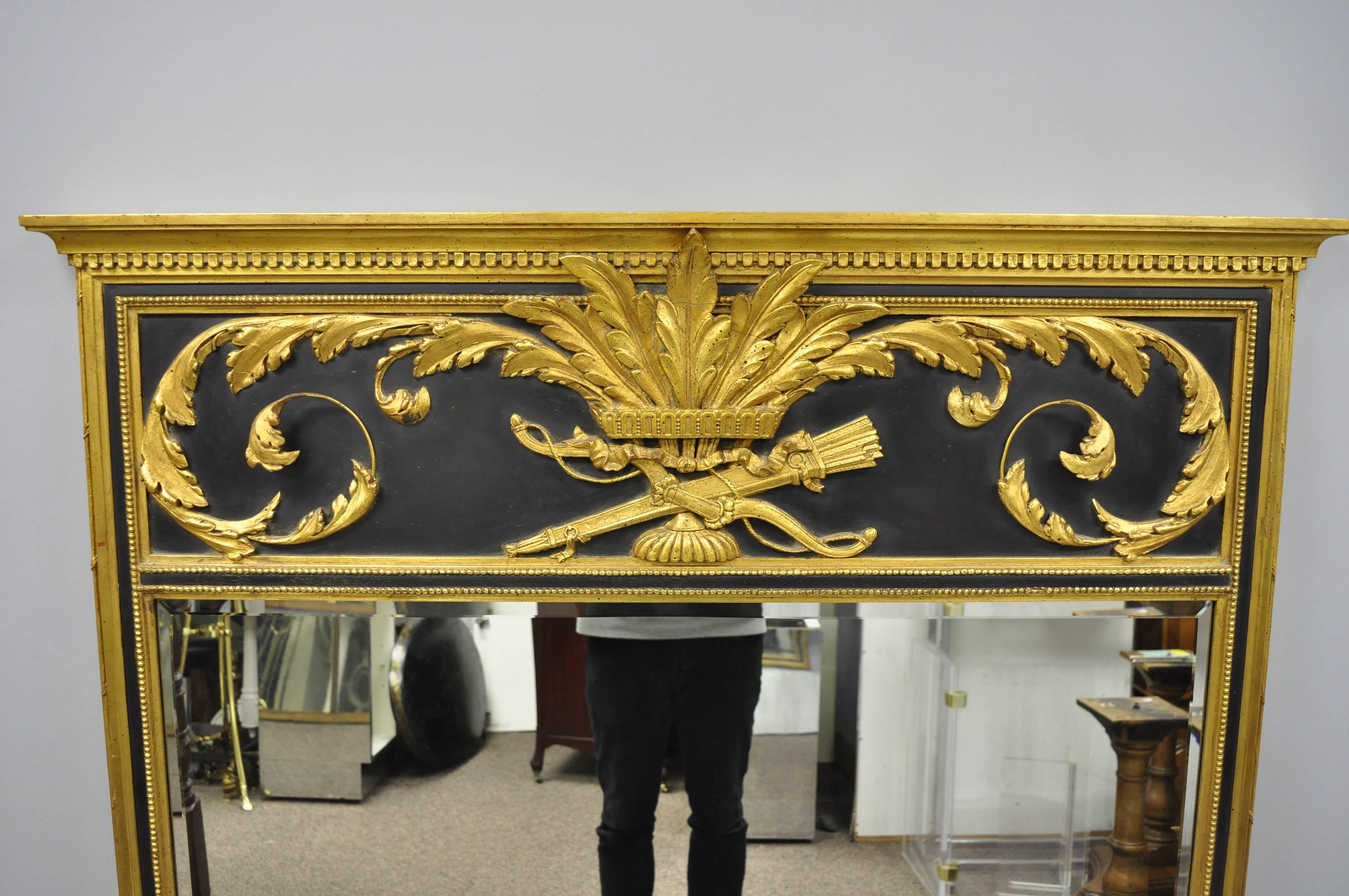 French Louis XV neoclassical style large black and gold giltwood trumeau wall mirror. Item features gold giltwood frame, bow and arrow designed crest with acanthus leaf scrollwork and black accents, beveled glass mirror, great style and form,