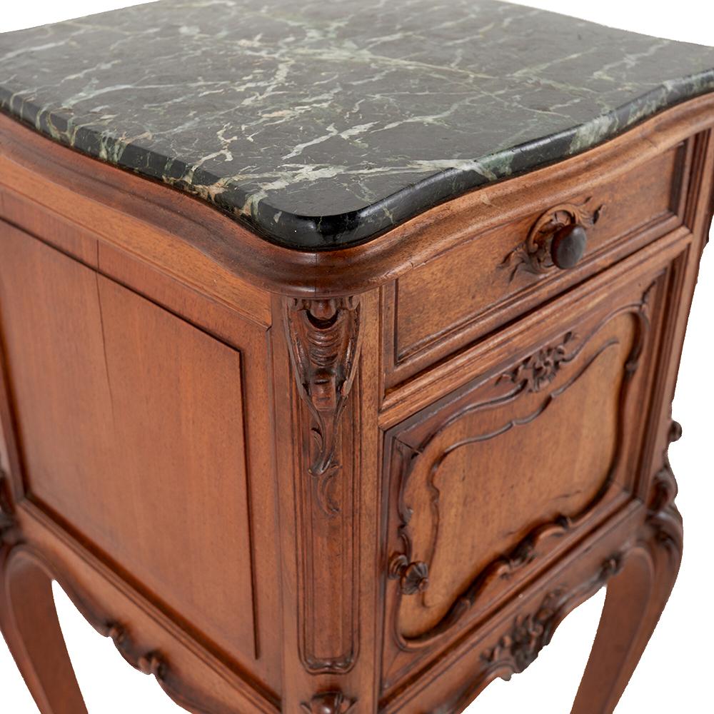 A highly-carved French Louis XV style walnut nightstand with an inset marble top, having a small drawer above a small cabinet, the whole raised on elegant serpentine legs.

 