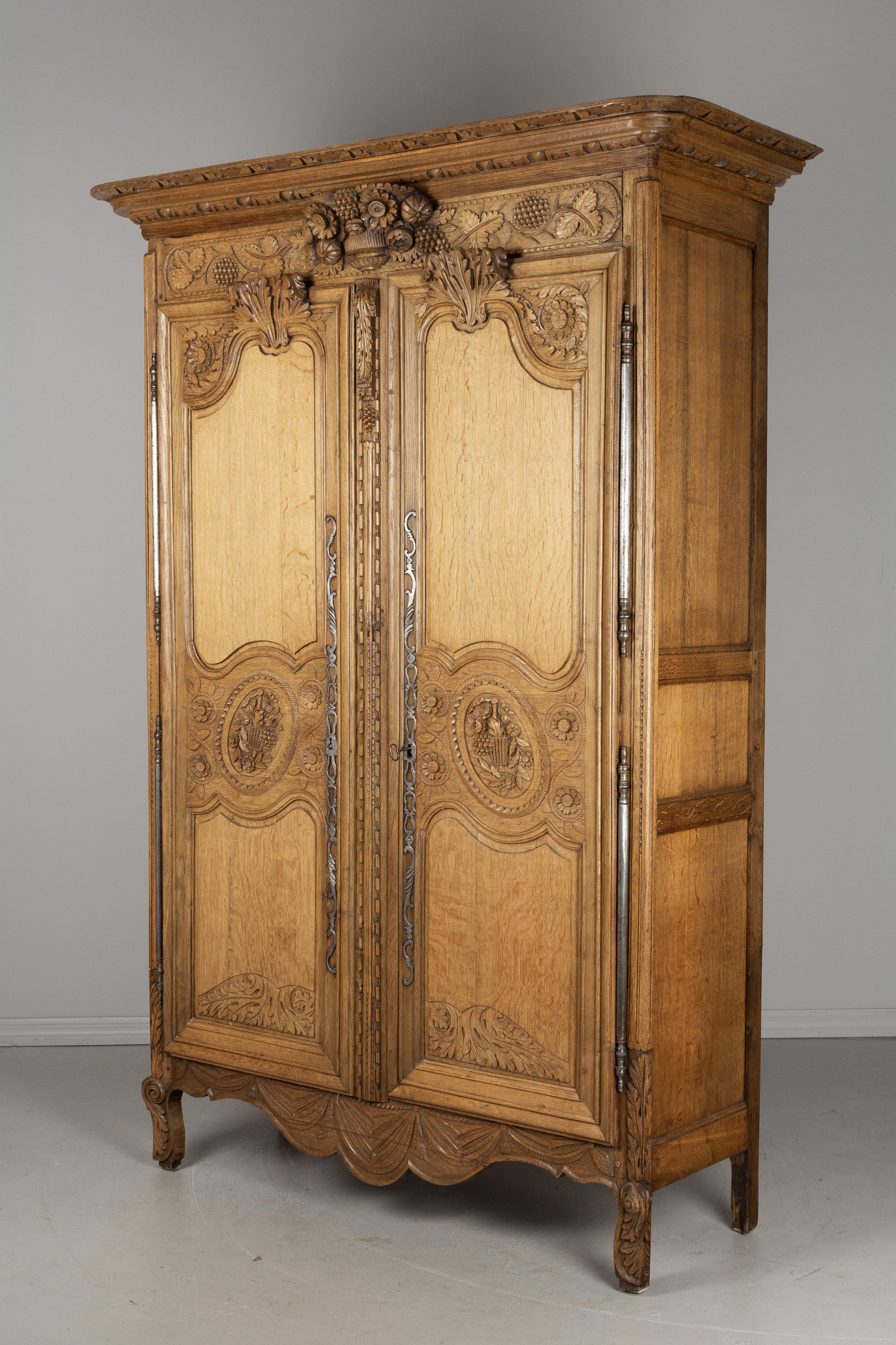 A 19th century Louis XV Country French bridal armoire from Normandy. Made of oak with fine hand carving throughout, including a three dimensional flower basket below the crown and large acanthus leaves above each door, grape vines and oval