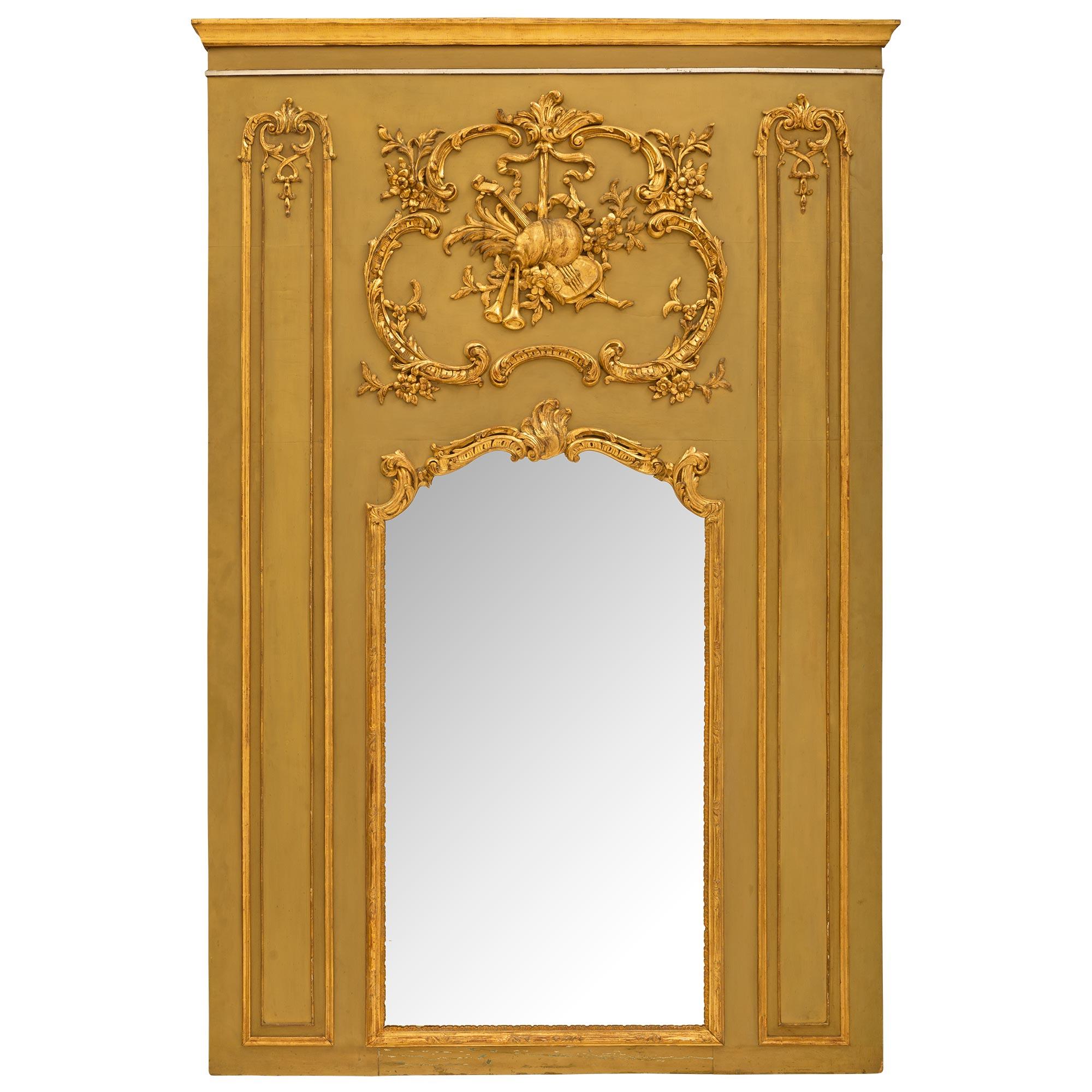 An exceptional French Louis XV or XVI st. patinated giltwood Trumeau. The background in patinated green is decorated by carved giltwood scrolls of acanthus leaves and flowers. The original mirror plate is framed in giltwood scrolls and reeded border