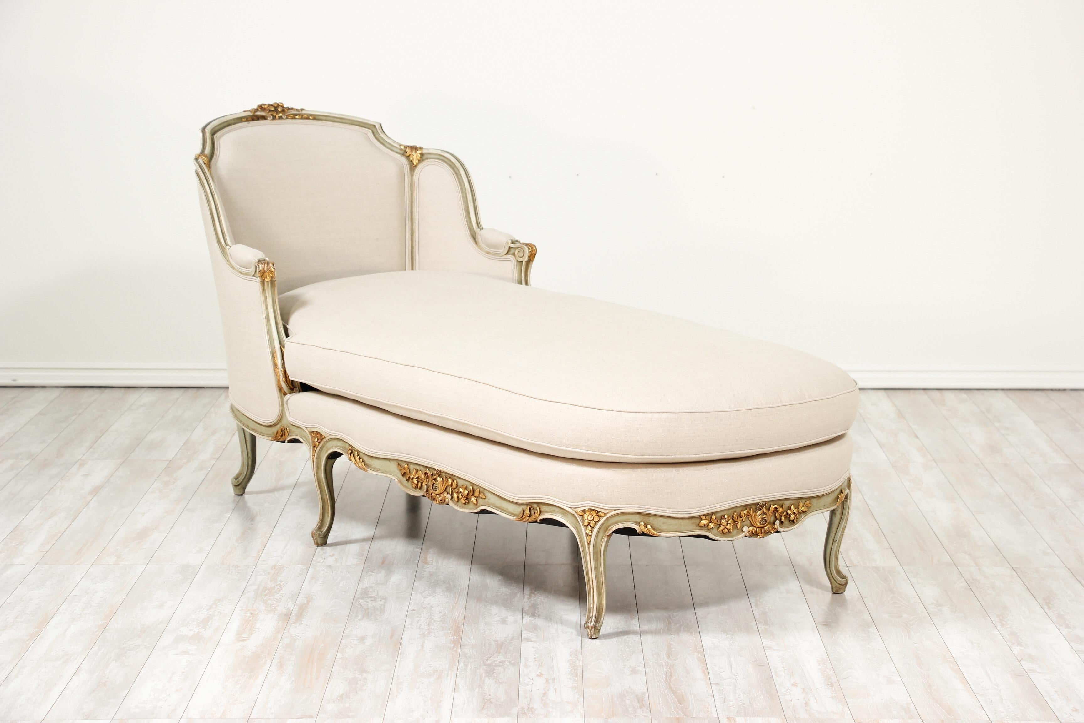 Luxurious, 1940s French Louis XV-style painted and parcel-gilt carved chaise lounge with new Belgian linen upholstery. 

This exquisite chaise features finely carved gilded floral decorations which accent it’s soft light olive-green and cream