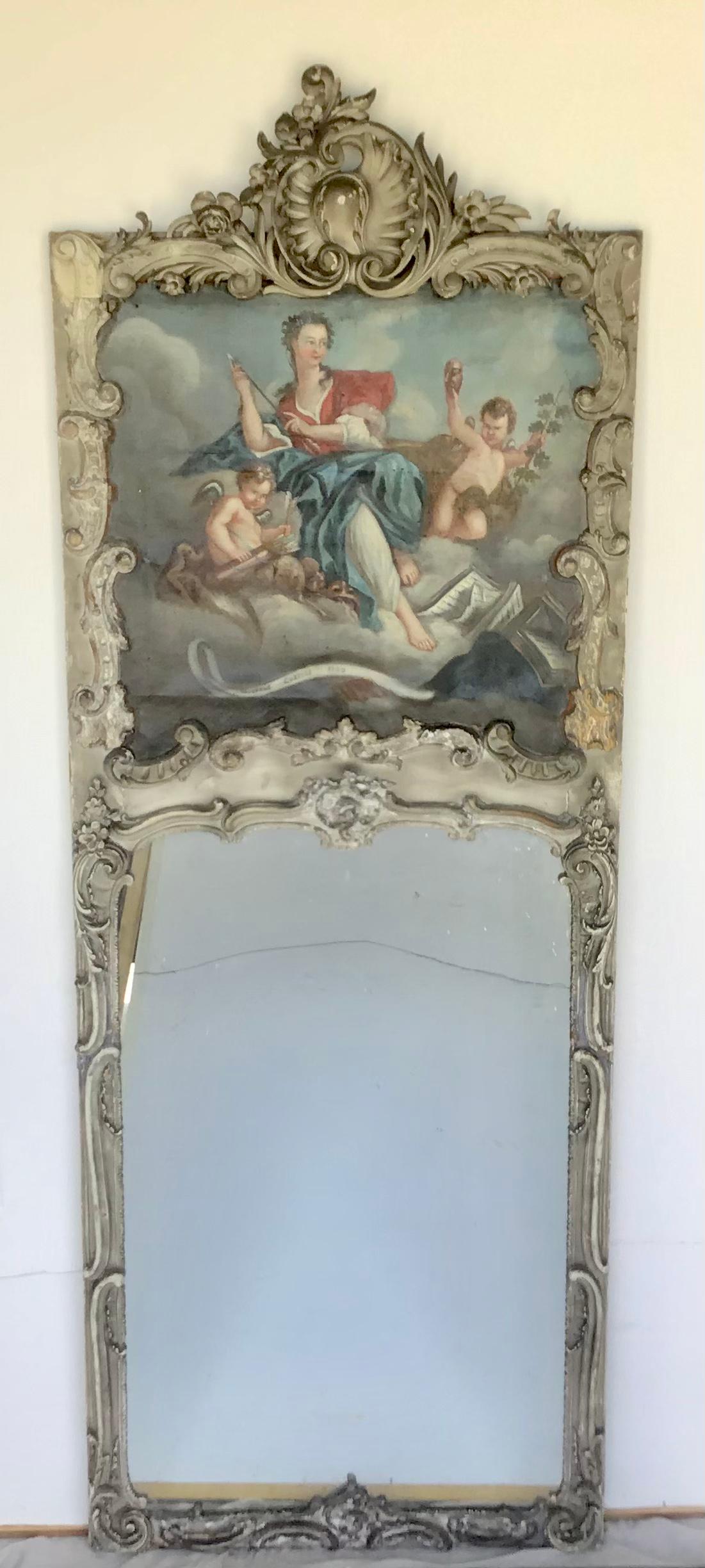 19th century French Louis XV painted trumeau combines a brilliantly hand carved frame surrounding a stunning painting depicting a maiden and cherubs in the clouds. The frame has a wonderful patinaed painted finish that highlights the contours and