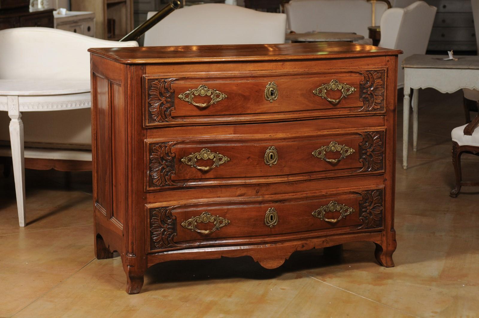 A French Louis XV period early 18th century walnut three-drawer commode from Lyon, with carved foliage and serpentine front. Crafted in Lyon during the reign of King Louis XV nicknamed the Bien-Aimé (the Beloved), this walnut commode features a