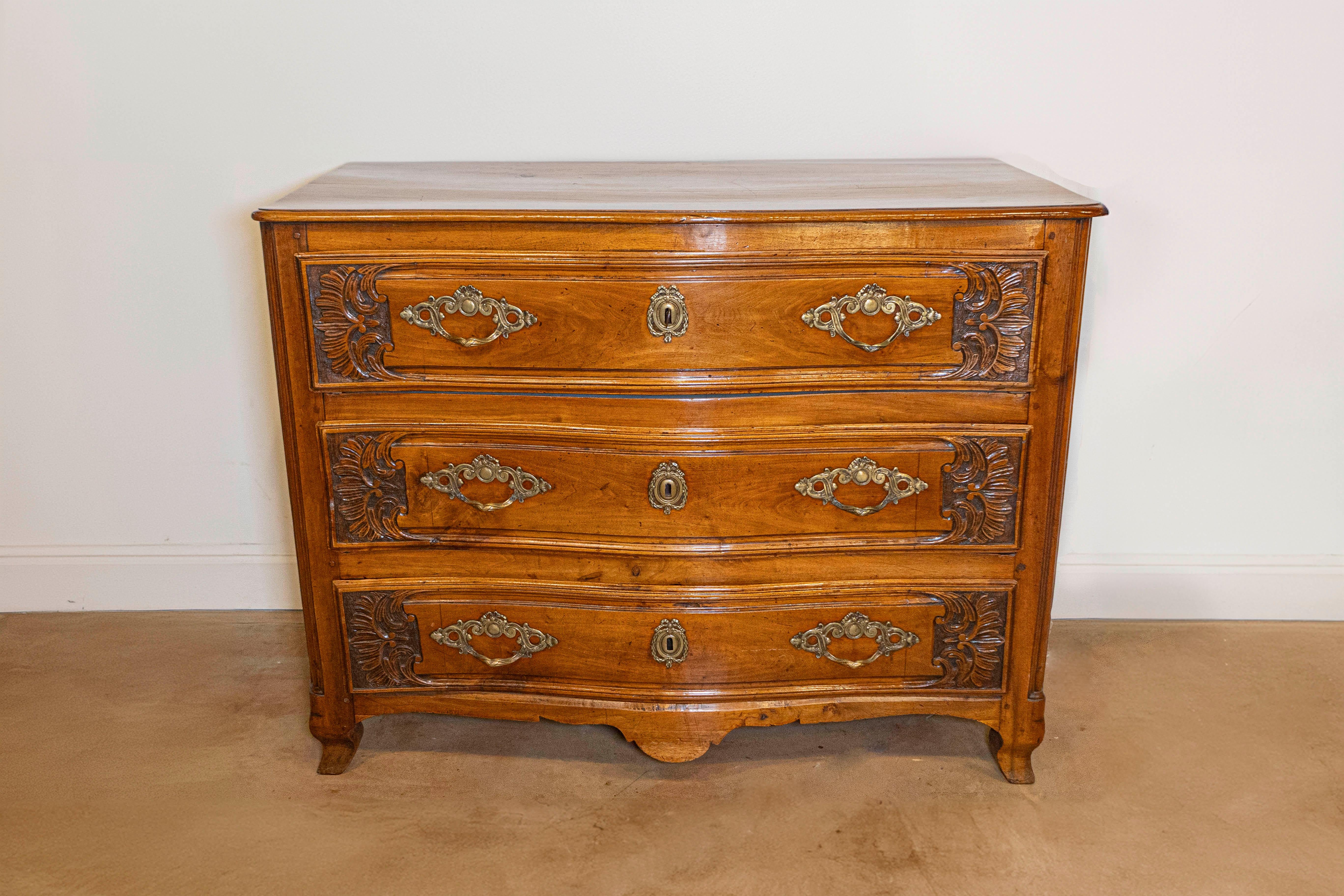 A French Louis XV period early 18th century walnut three-drawer commode from Lyon, with carved foliage and serpentine front. Crafted in Lyon during the reign of King Louis XV nicknamed the Bien-Aimé (the Beloved), this walnut commode features a