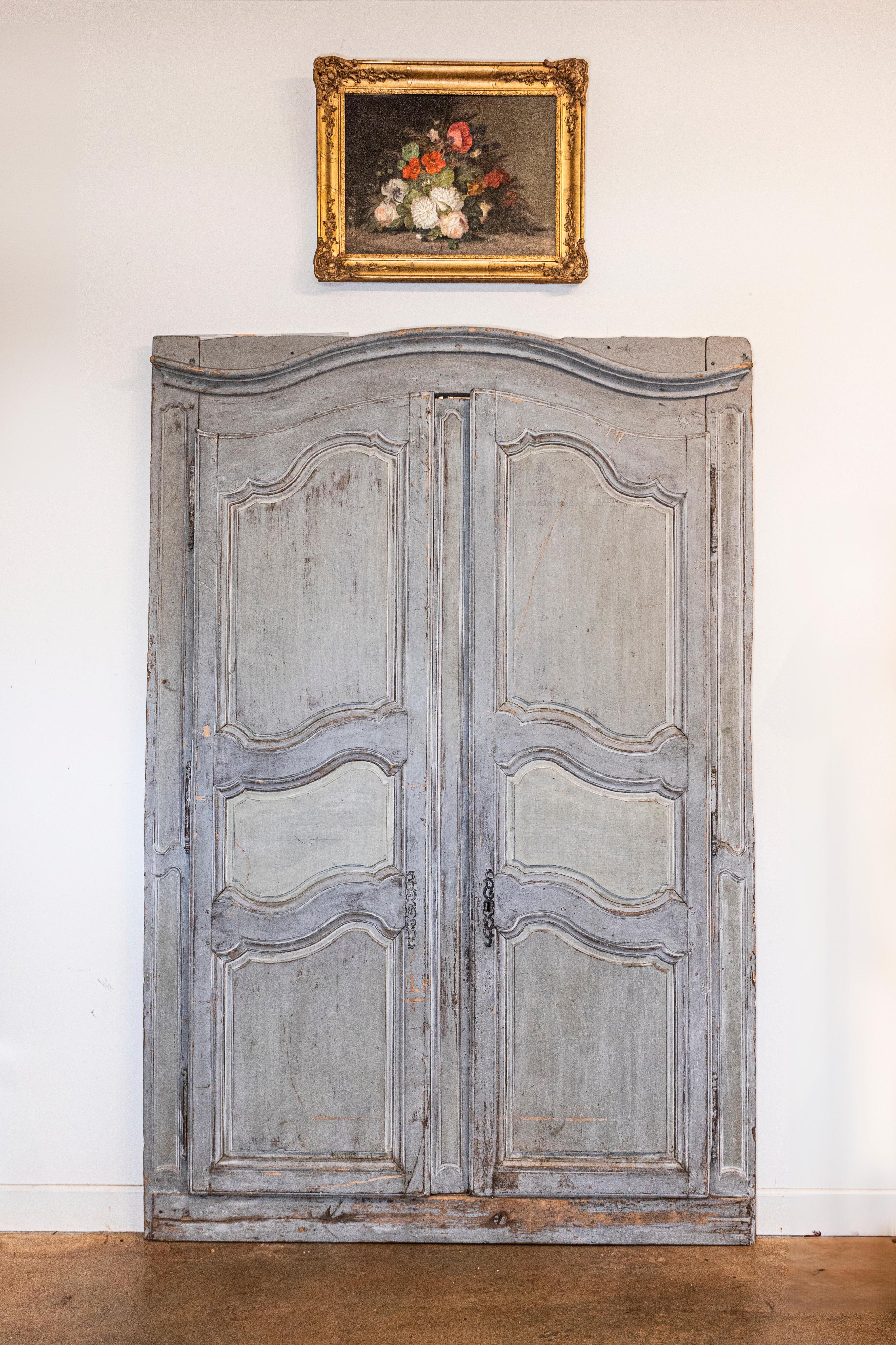 A pair of French Louis XV period blue gray painted wood double doors from circa 1750 with blue gray painted finish and carved panels. These enchanting Louis XV period double doors, originating from circa 1750, are a testament to the refined elegance