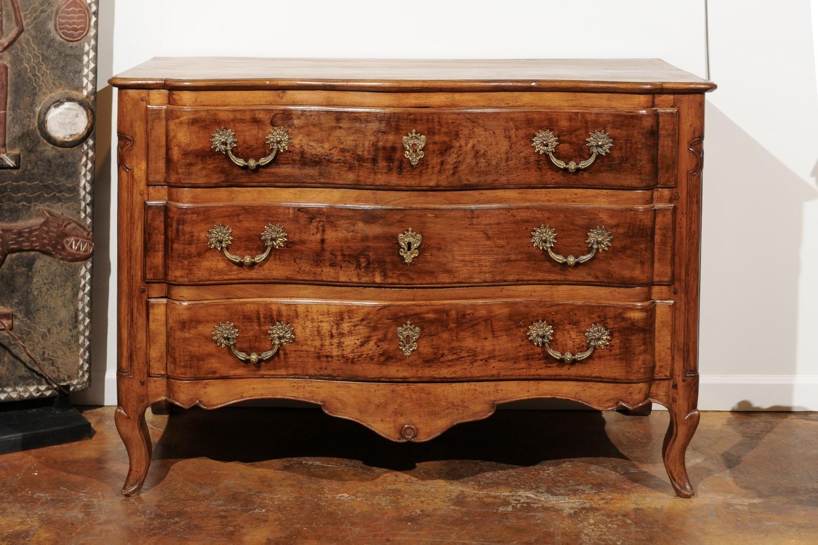 A French Louis XV period walnut commode from the mid-18th century, with serpentine front, three drawers and scalloped apron. Born in France during the reign of King Louis XV nicknamed at the time the Bien-Aimé (the beloved), this exquisite walnut