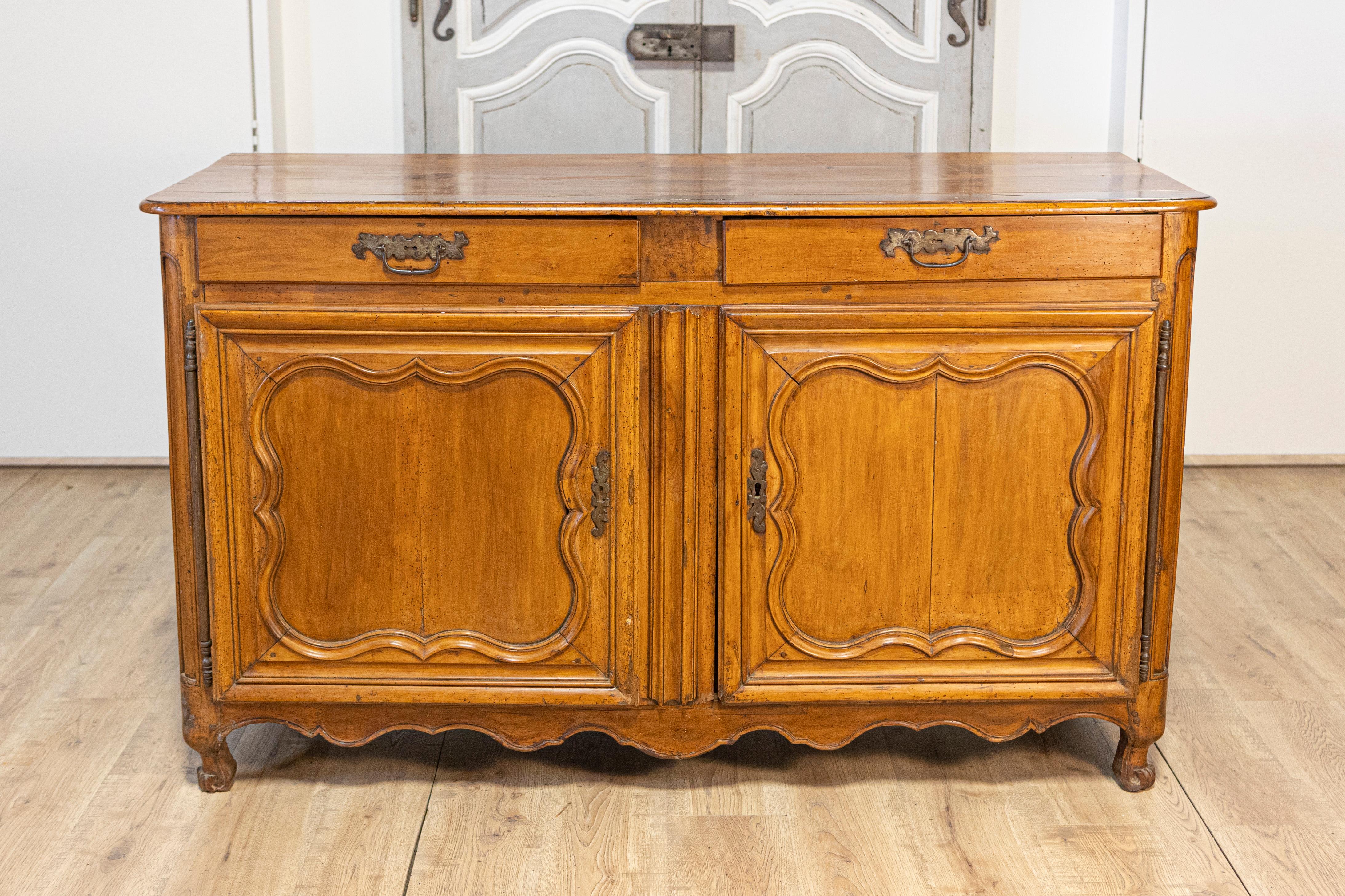 Un buffet francese in noce del periodo Luigi XV, risalente al 1770 circa, con due cassetti su ante e gonna intagliate. Questo buffet francese in noce del periodo Luigi XV, risalente al 1770 circa, emana l'eleganza senza tempo e la maestria