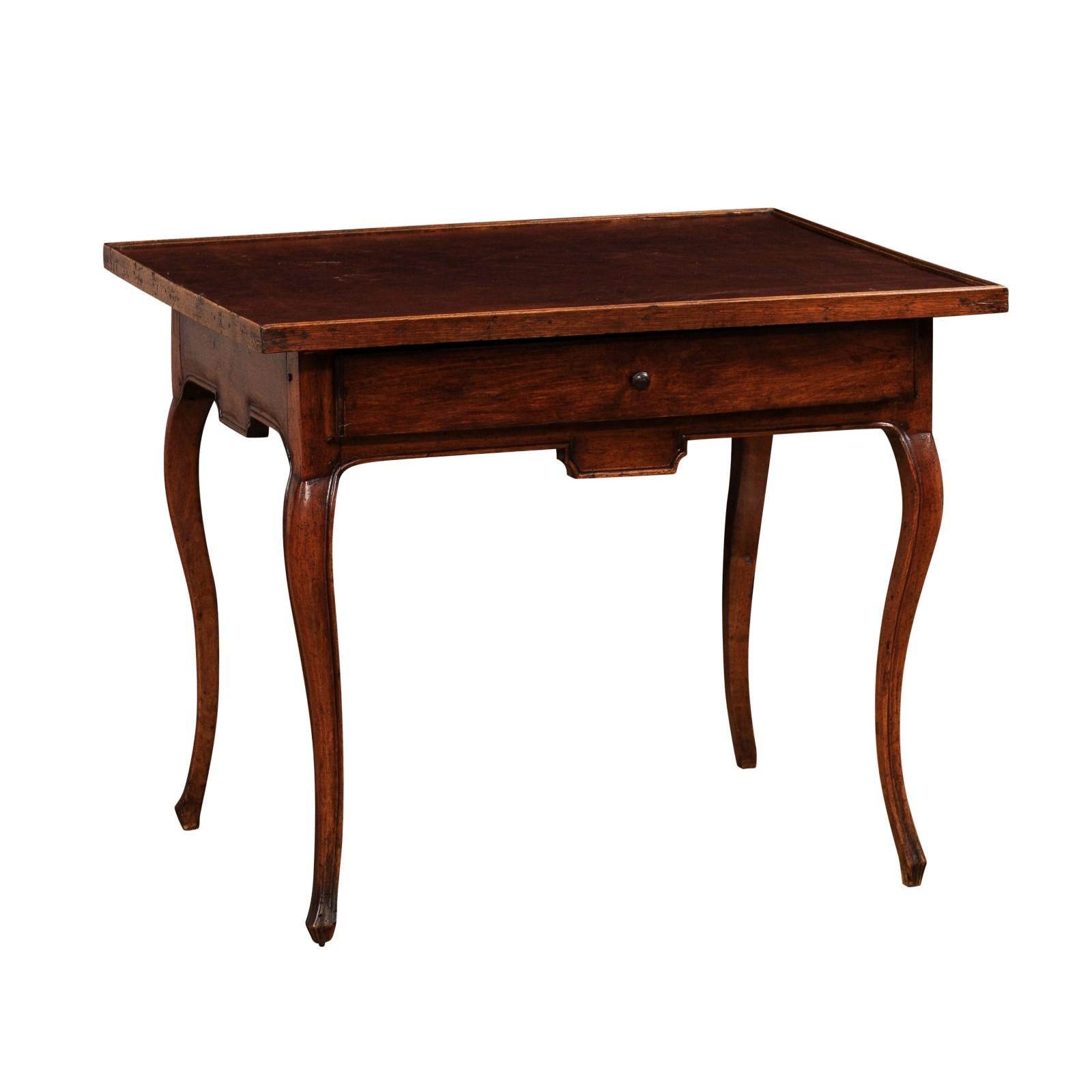 A French Louis XV period game table from the 18th century with brown leather top, single drawer, carved apron and cabriole legs. This exquisite French Louis XV period game table, crafted in the 18th century, is a testament to the timeless allure of