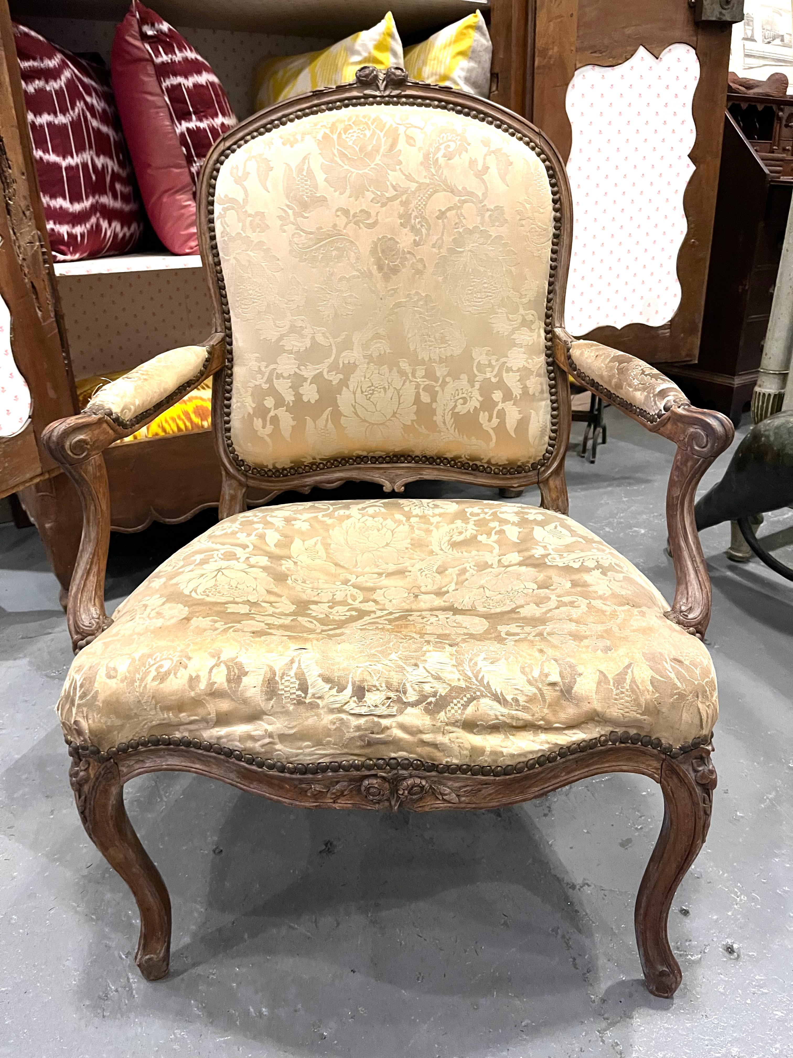 Fino sillón de época Luis XV Fauteuil a la Reine de haya, bellamente esculpido y tallado con motivos florales y de otro tipo en la cresta y las barras del asiento, así como en las patas cabriolé, actualmente tapizado en tela de seda de Damasco muy