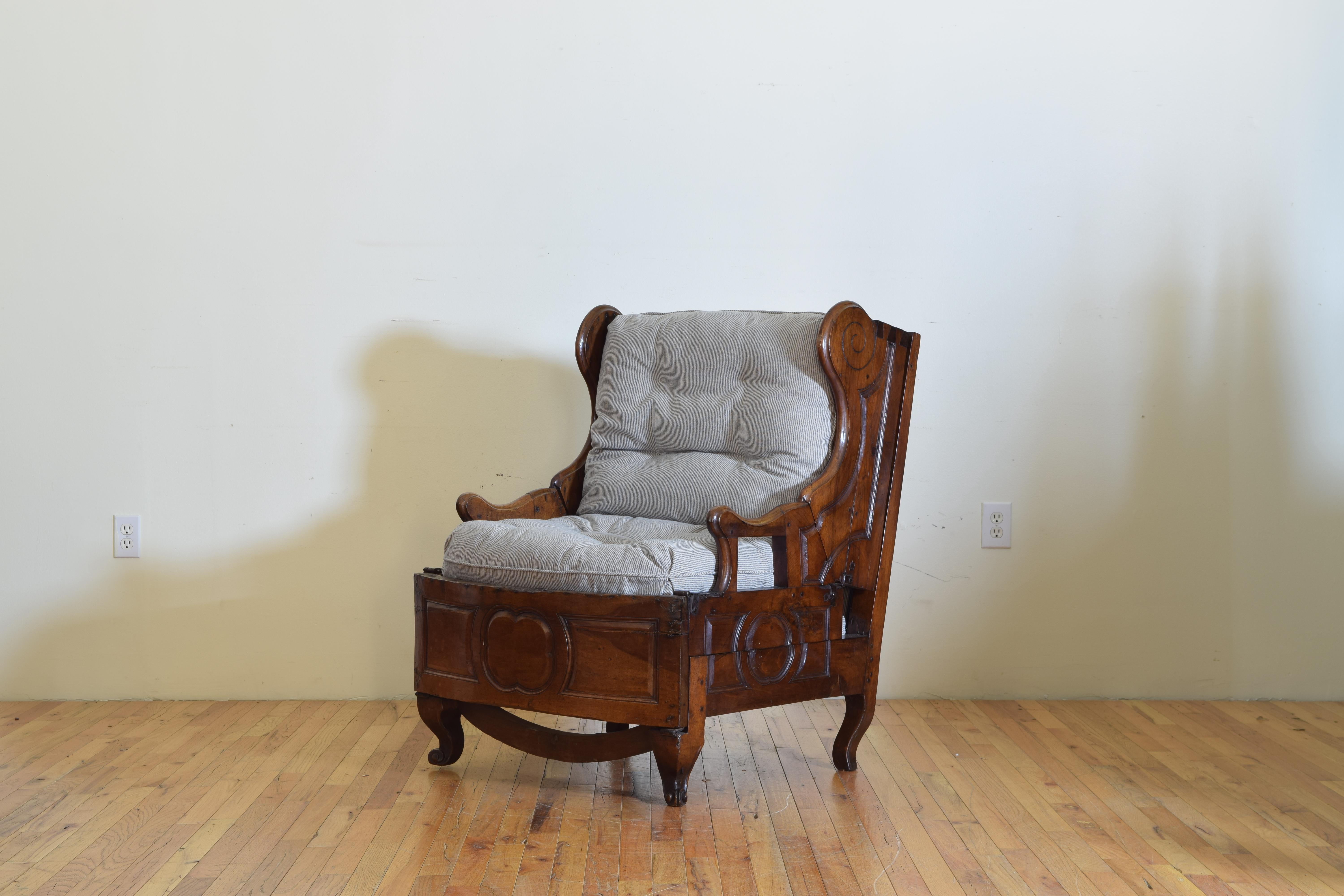 This large scale bergere/fauteuil hybrid has generous down filled cushions and folds down and over into a bed, with small carved handles and quatrefoil panels, and escargot feet.