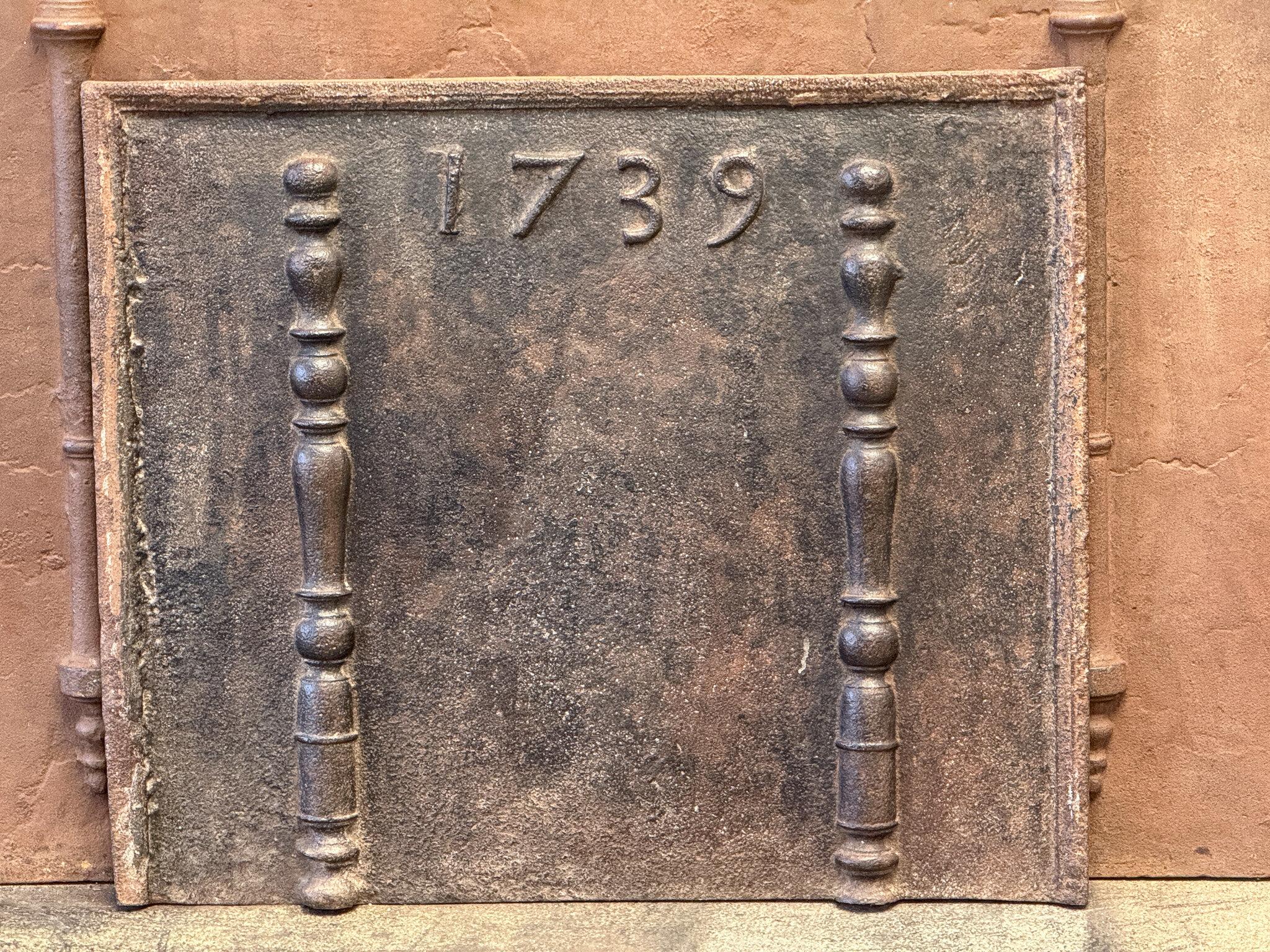 18th century French Louis XV Period fireback. The date of production, 1739, is cast in the fireback. The pillars refer to the club of Hercules and symbolize strength and the unknown.

The fireback is made of cast iron and has a natural brown patina.