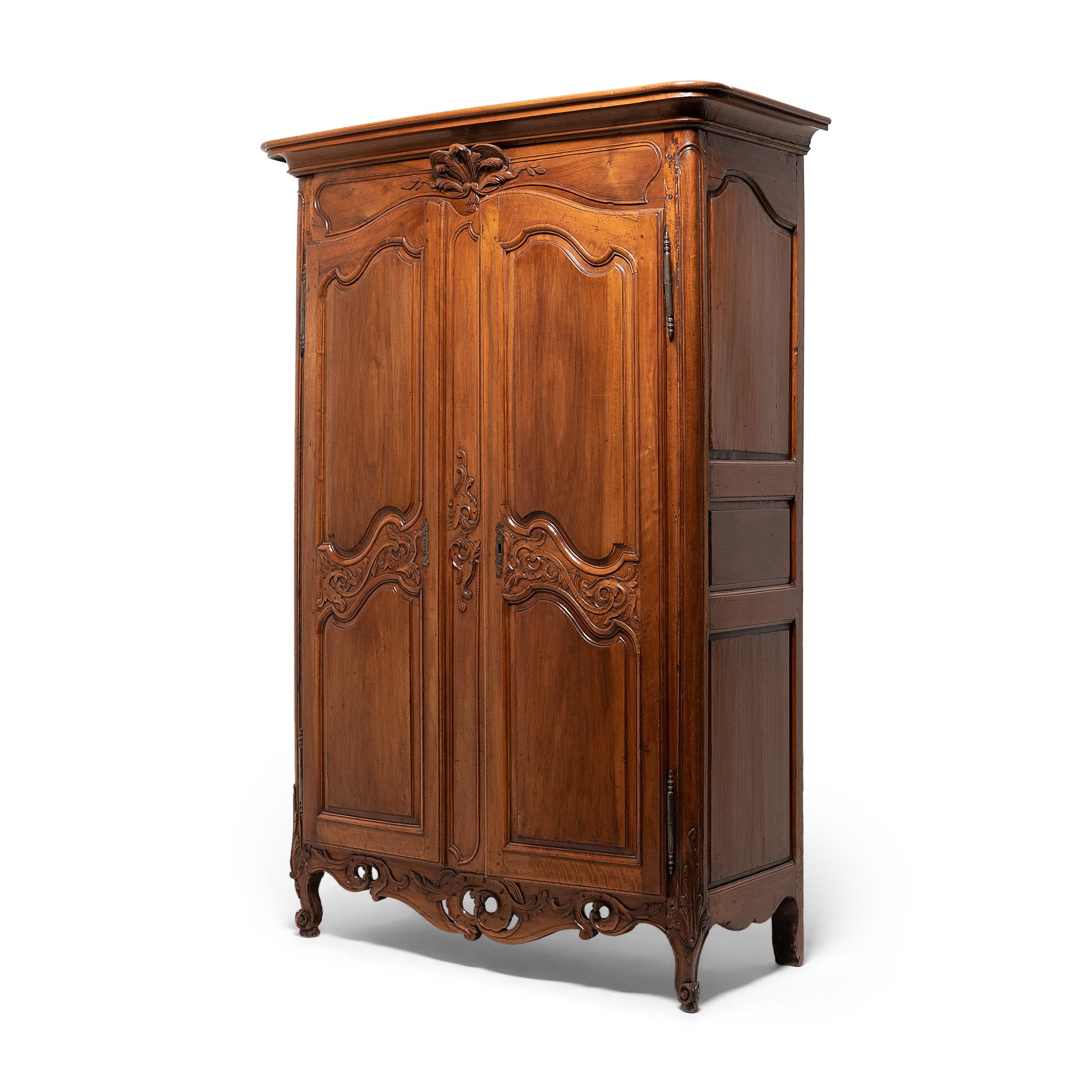 This elegant French armoire dates to the mid- to late-18th century and wonderfully exemplifies the French Provincial and Louis XV styles. The cabinet front is beautifully decorated with cartouche panels framed with beaded edging and interspersed