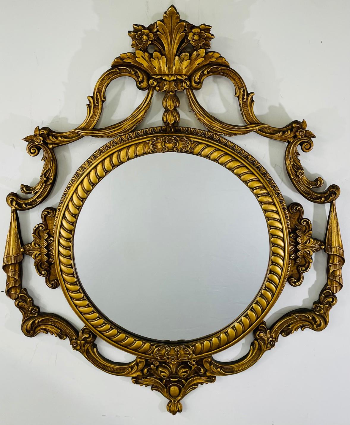 A French Louis XV Rococo style gilt wood circular wall or mantel mirror presenting exquisite wood carving details. The mirror features acanthus and scrolls design flowing around the circular mirror. The whole frame is finely gilded. Elegant and