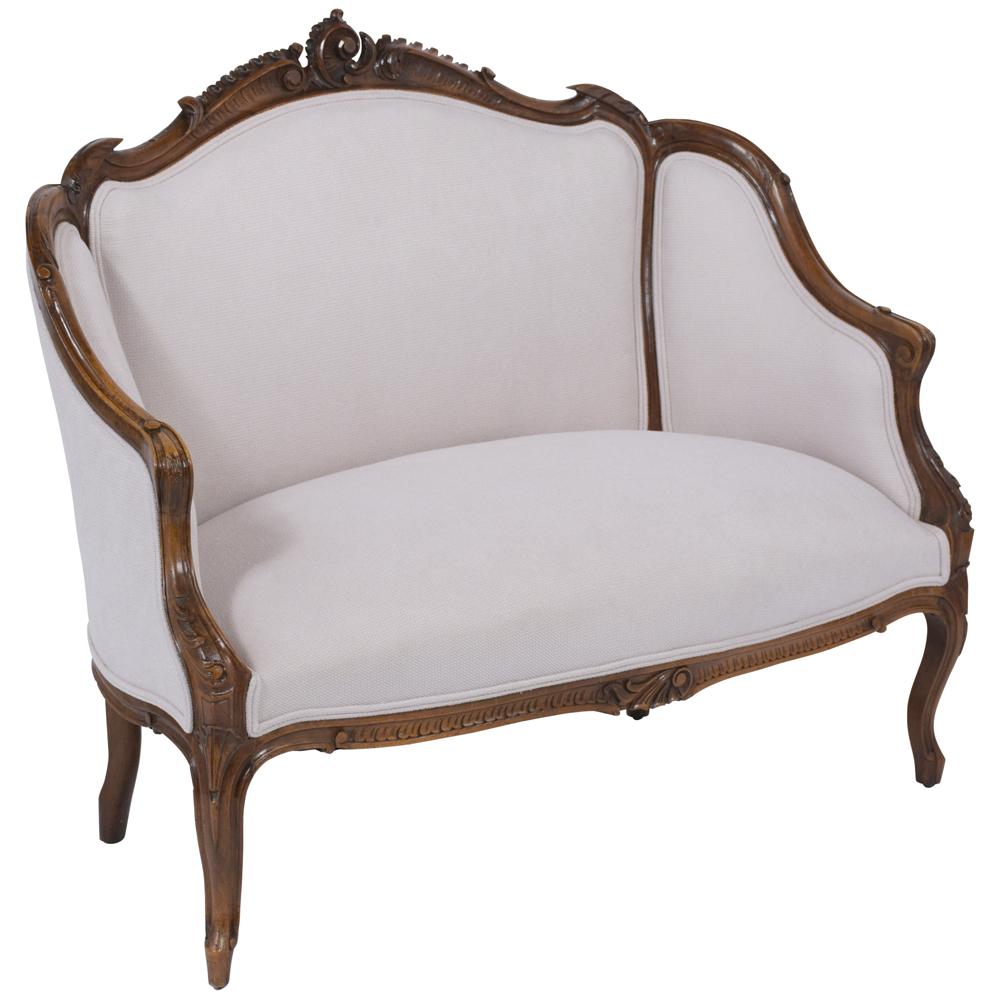 An elegant antique French Louis XV settee handcrafted out of walnut wood and features finely hand-carved details throughout the frame and is finished in a walnut color with a beautiful patina finish. This 1870s loveseat has been newly upholstered in