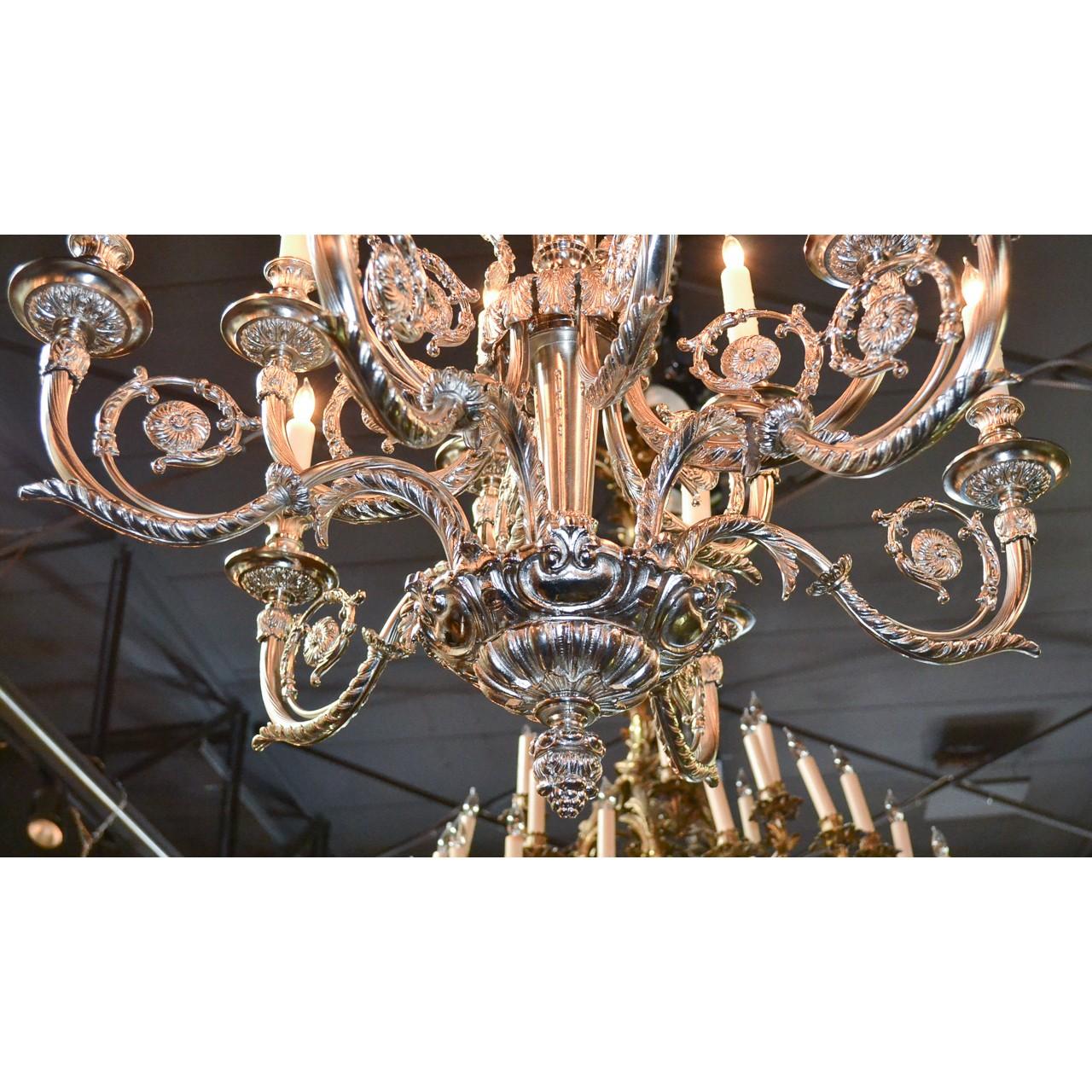 Phenomenal French Louis XV style silver-plate on bronze twelve-light chandelier of paragon quality. The foilate canopy atop exquisite cherubic and acanthus leaf surmounts. The trumpet vase shaped stem adorned with twelve ornately scrolled arms with
