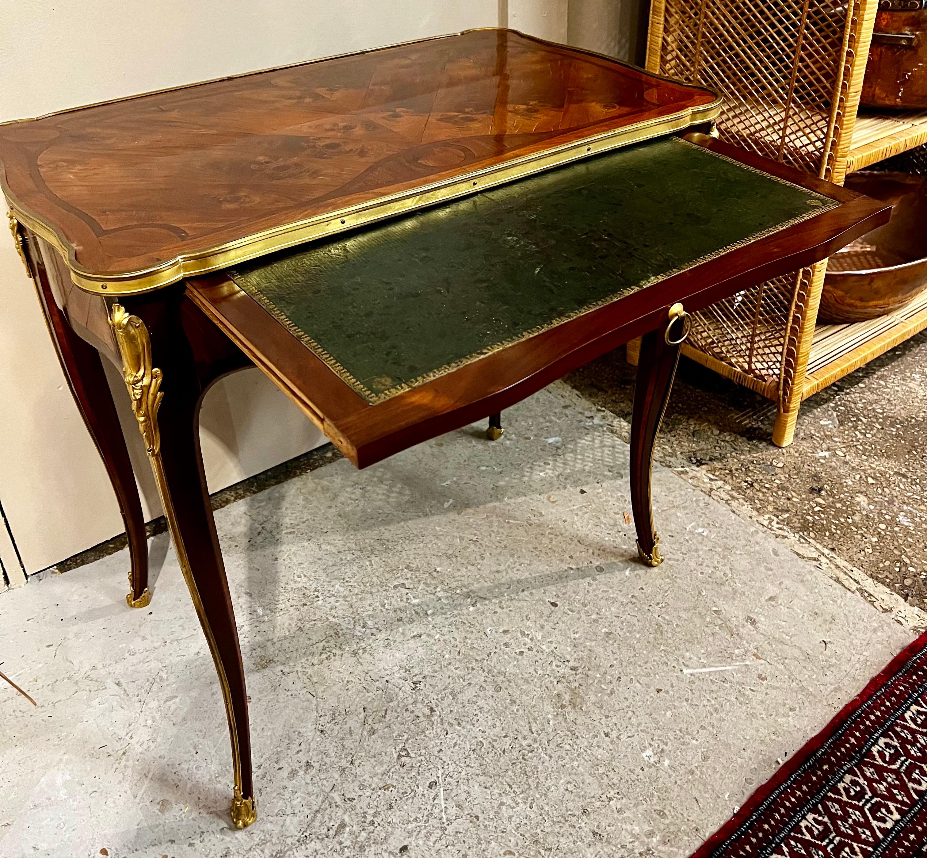 Questa piccola scrivania francese Luigi XV incarna l'eleganza dell'artigianato francese del XVIII secolo. Il piano in intarsio è impreziosito da decorazioni in bronzo ormolu, che aggiungono un tocco di lusso dorato. Una superficie di scrittura in