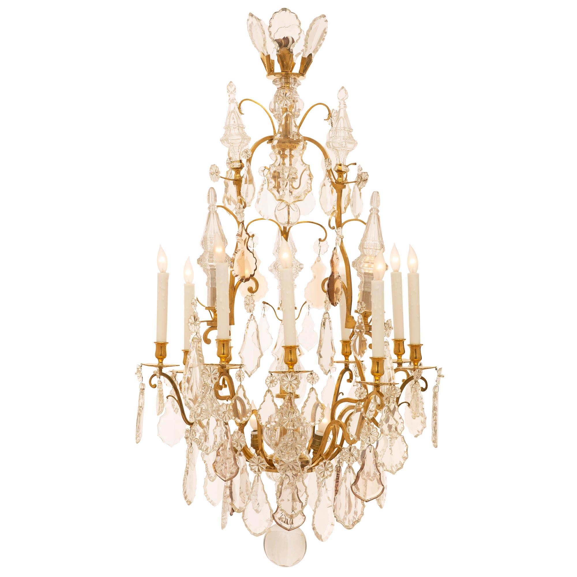 An exquisite French Louis XV st. fifteen light Baccarat crystal chandelier. With nine impressive double S scrolled ormolu arms opulently decorated with amethyst and clear crystal lyre and kite shaped pendants above the smoky crystal ball. At the