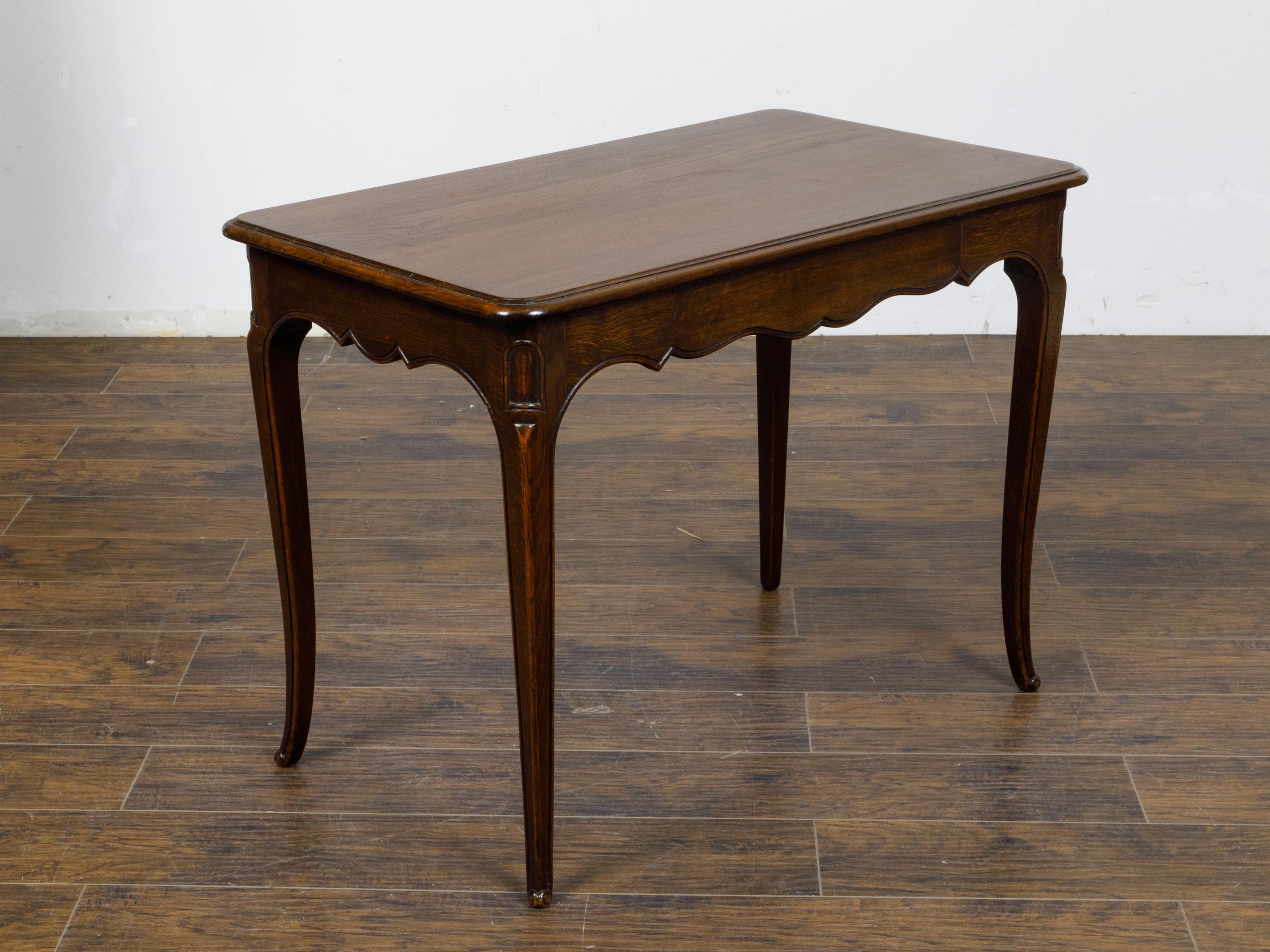 A French Louis XV style oak side table from circa 1900 with single drawer, scalloped apron, curving legs and scrolling feet. This exquisite French Louis XV style oak side table, circa 1900, perfectly embodies the elegance and grace of early