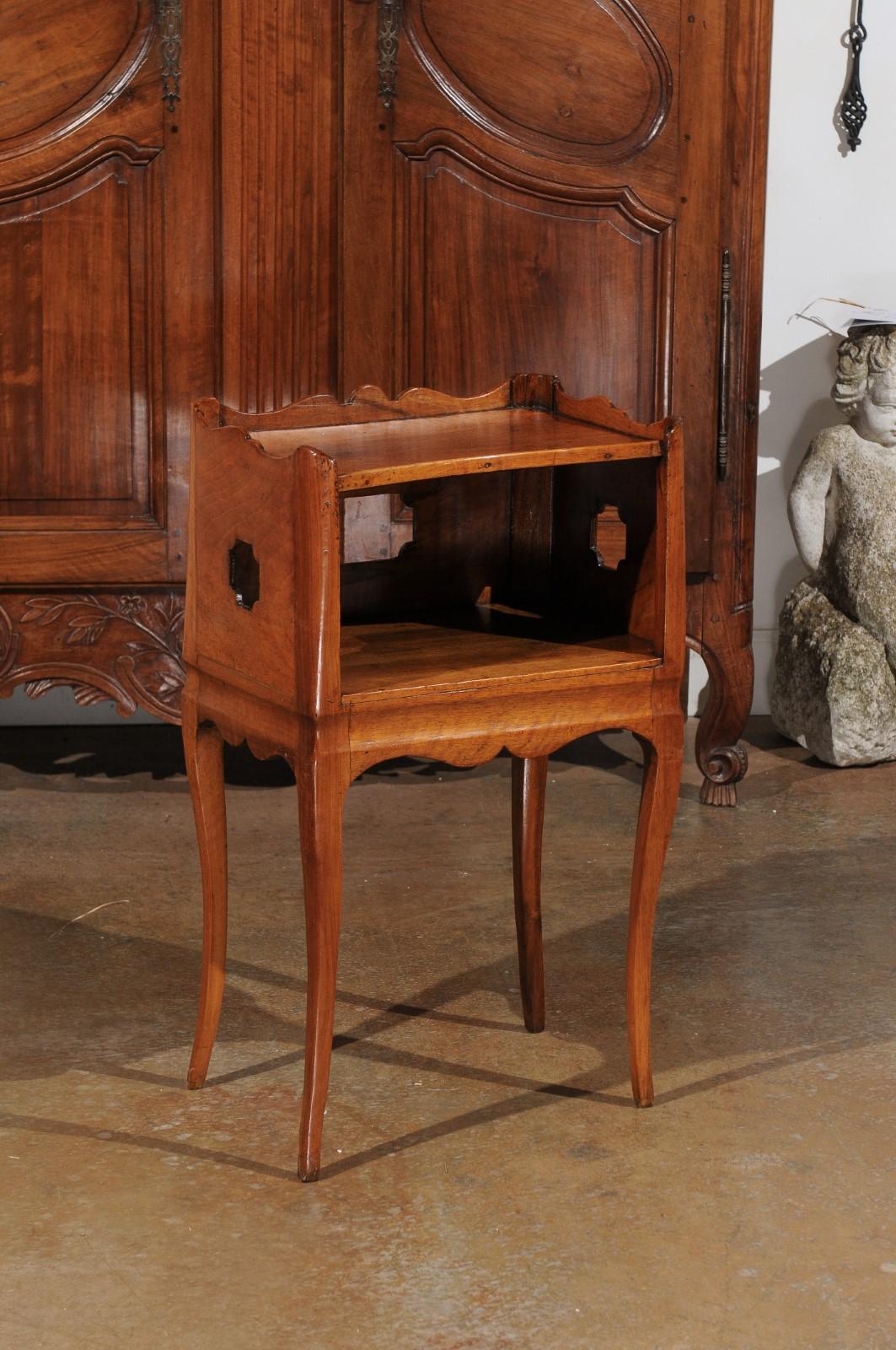 A French Louis XV style wooden bedside table from the 19th century, with tray top, pierced motifs and lateral drawer. Created in France during the 19th century, this 