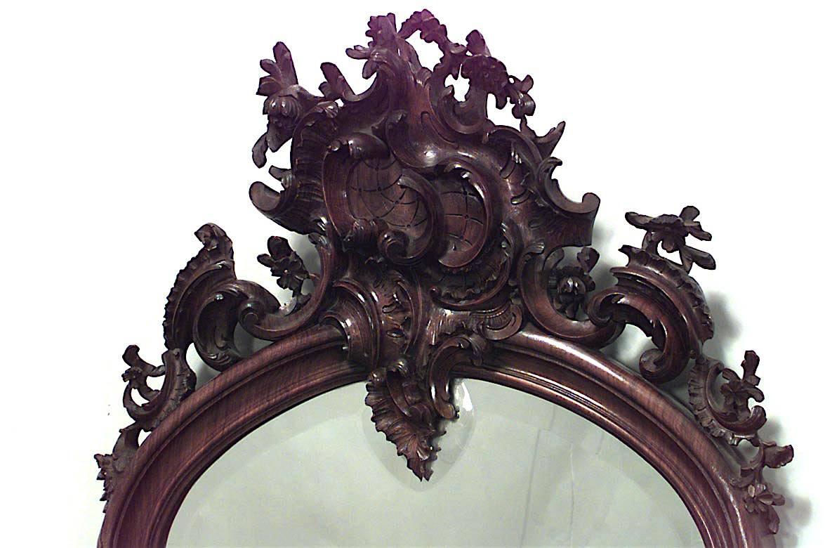 French Louis XV-style (19th Century) rosewood vertical shaped wall mirror with beveled glass and a carved floral scroll design frame.
