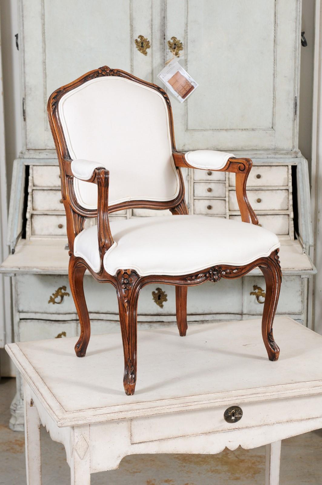 A French Louis XV style child's chair from the 19th century, with new upholstery. Created in France during the 19th century, this wooden child's chair charms us with its petite proportions and graceful Louis XV style lines. Carved with petite