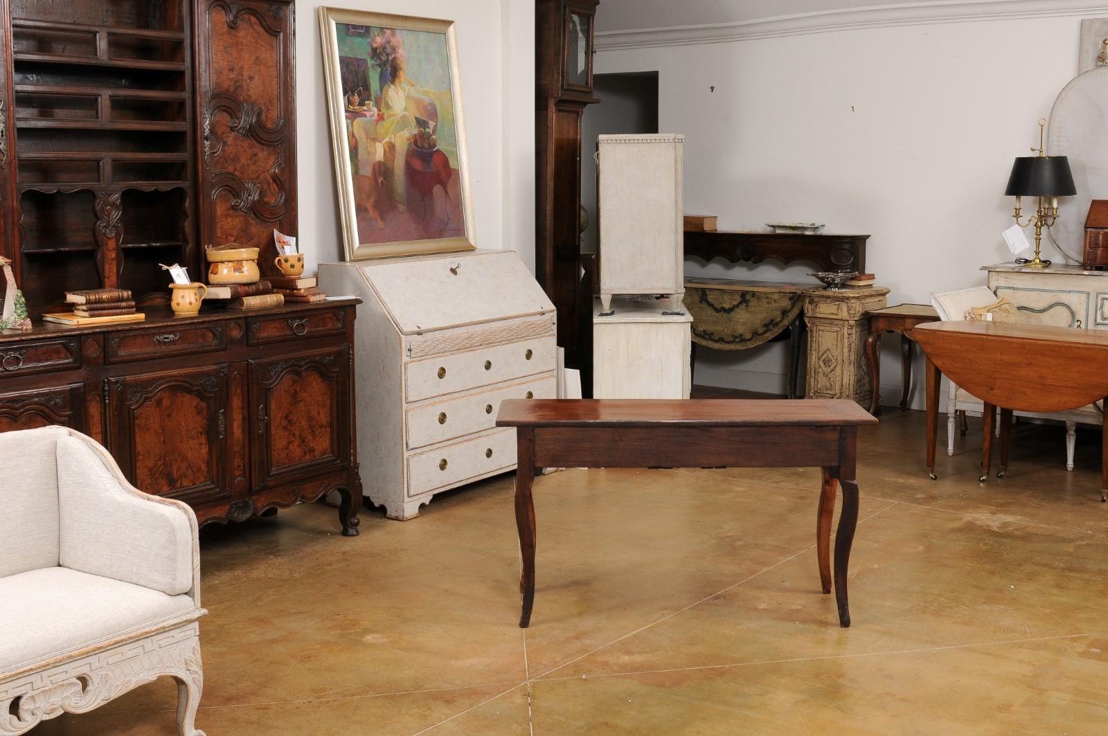 A French Louis XV style walnut console table from the 19th century, with three drawers, carved apron and cabriole legs. Created in France during the 19th century, this walnut console table features a rectangular top with central board, sitting above