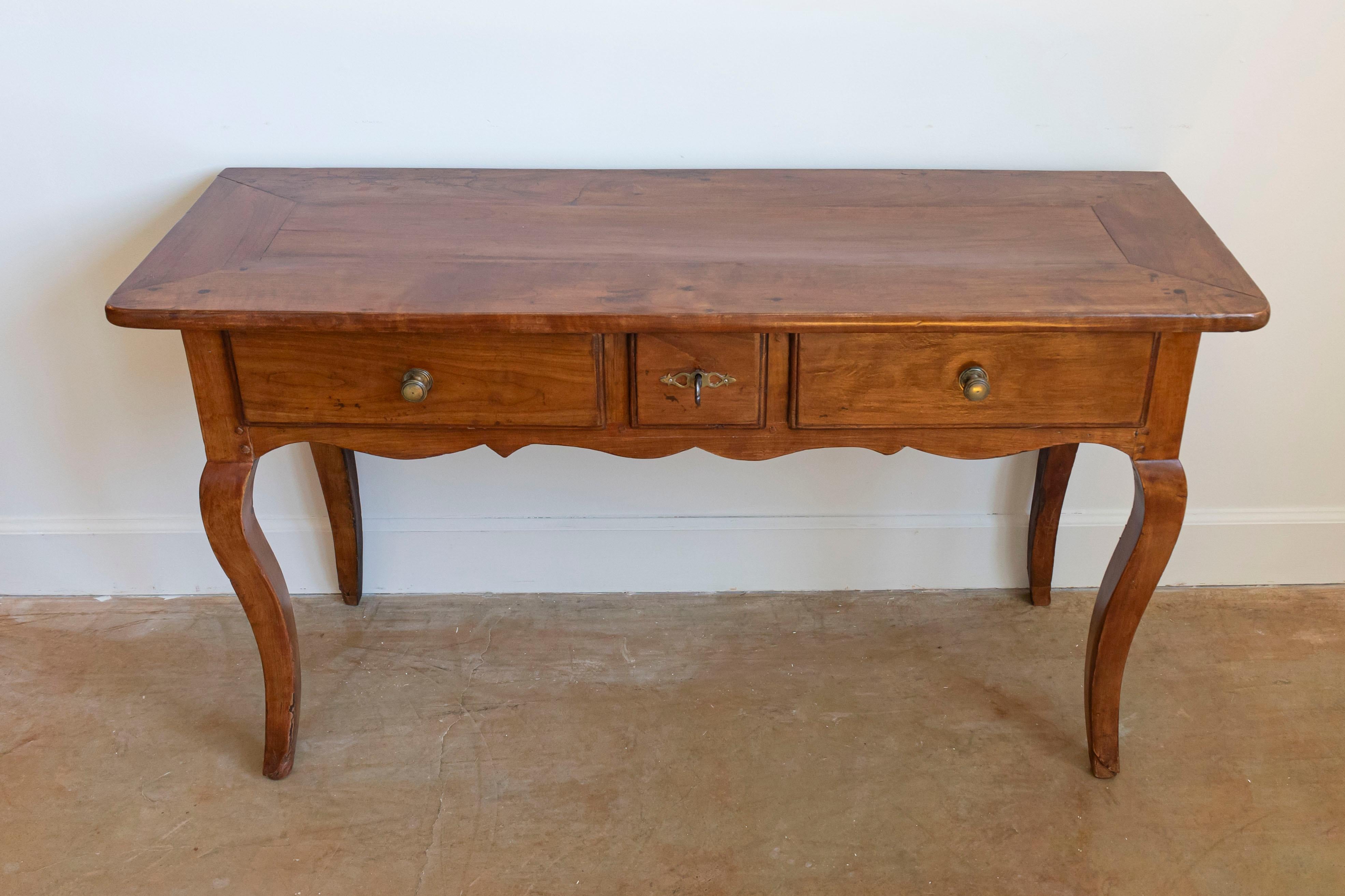 A French Louis XV style walnut console table from the 19th century, with three drawers, carved apron and cabriole legs. Created in France during the 19th century, this walnut console table features a rectangular top with central board, sitting above