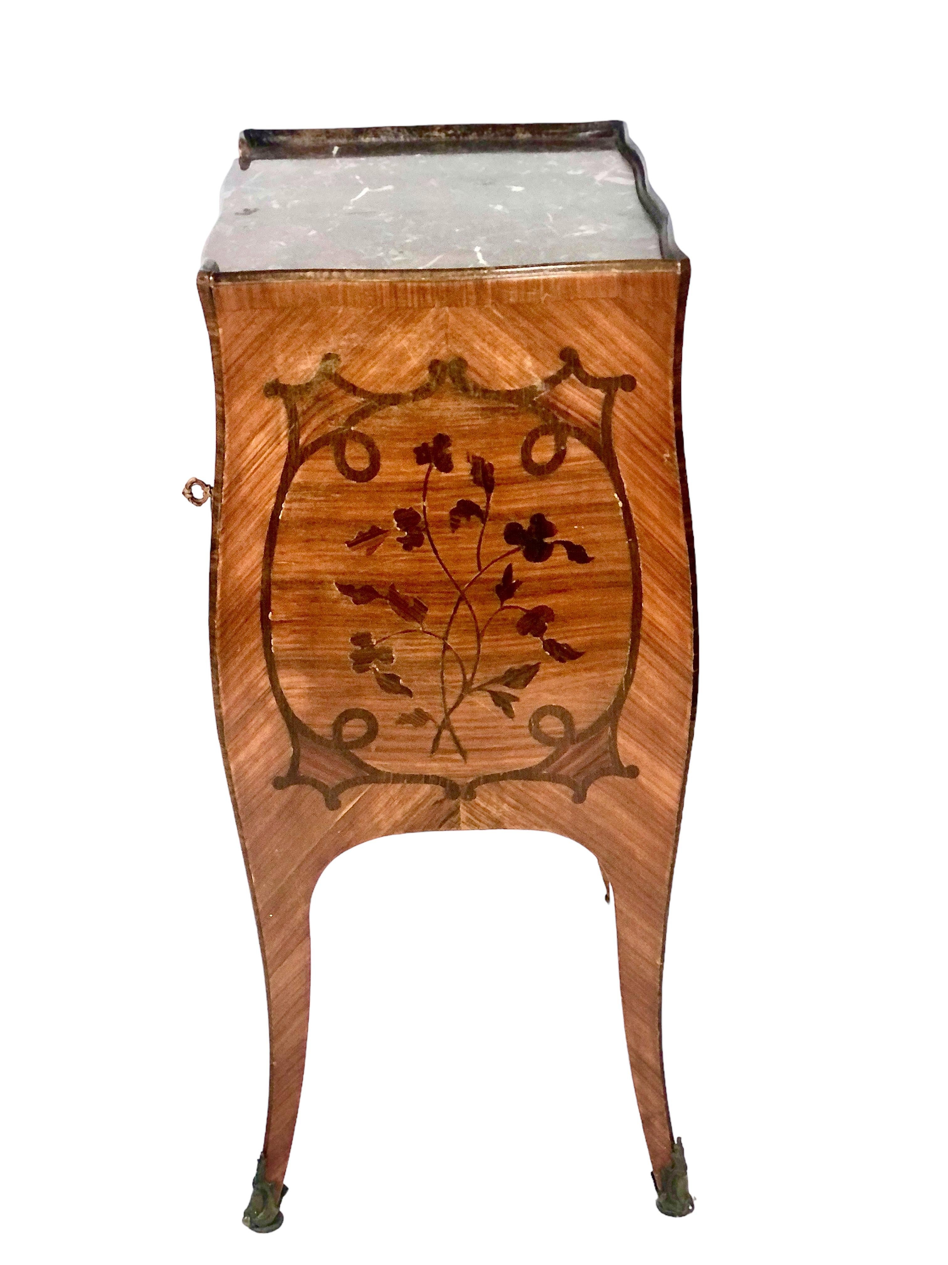 A fine, Parisian Louis XV style, marquetry-inlaid rosewood bedside table, featuring four curved sides and gently tapering legs. Fitted with fine gilt bronze escutcheons and mounts, and retaining the original dark red marble top, it has two small