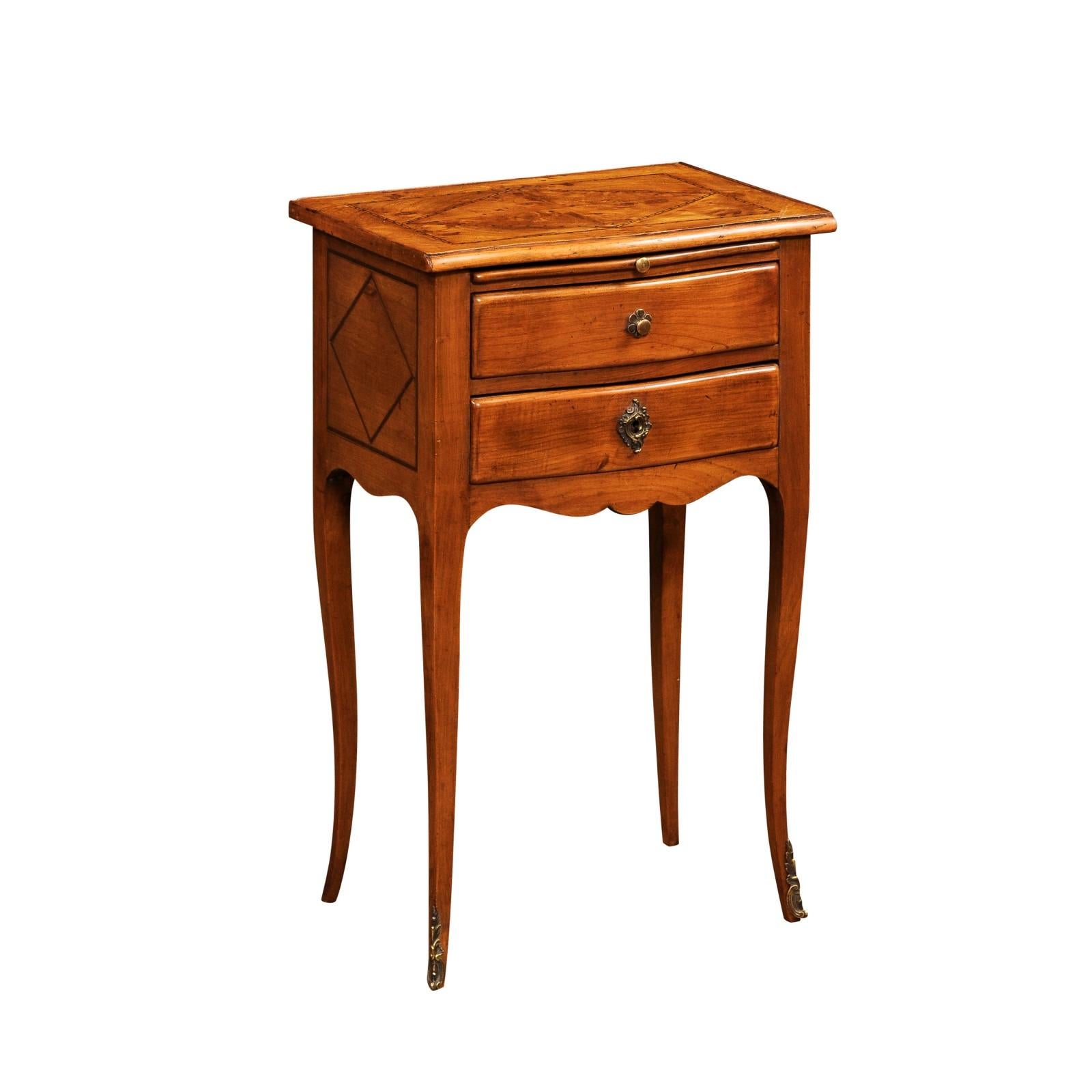 Table de chevet de style Louis XV en merisier, ronce de noyer et acajou du 20e siècle, avec un plateau incrusté de placage de quartier, deux tiroirs et une tirette sur des pieds cabriole avec des montures en bronze. Créée en France au cours du 20e