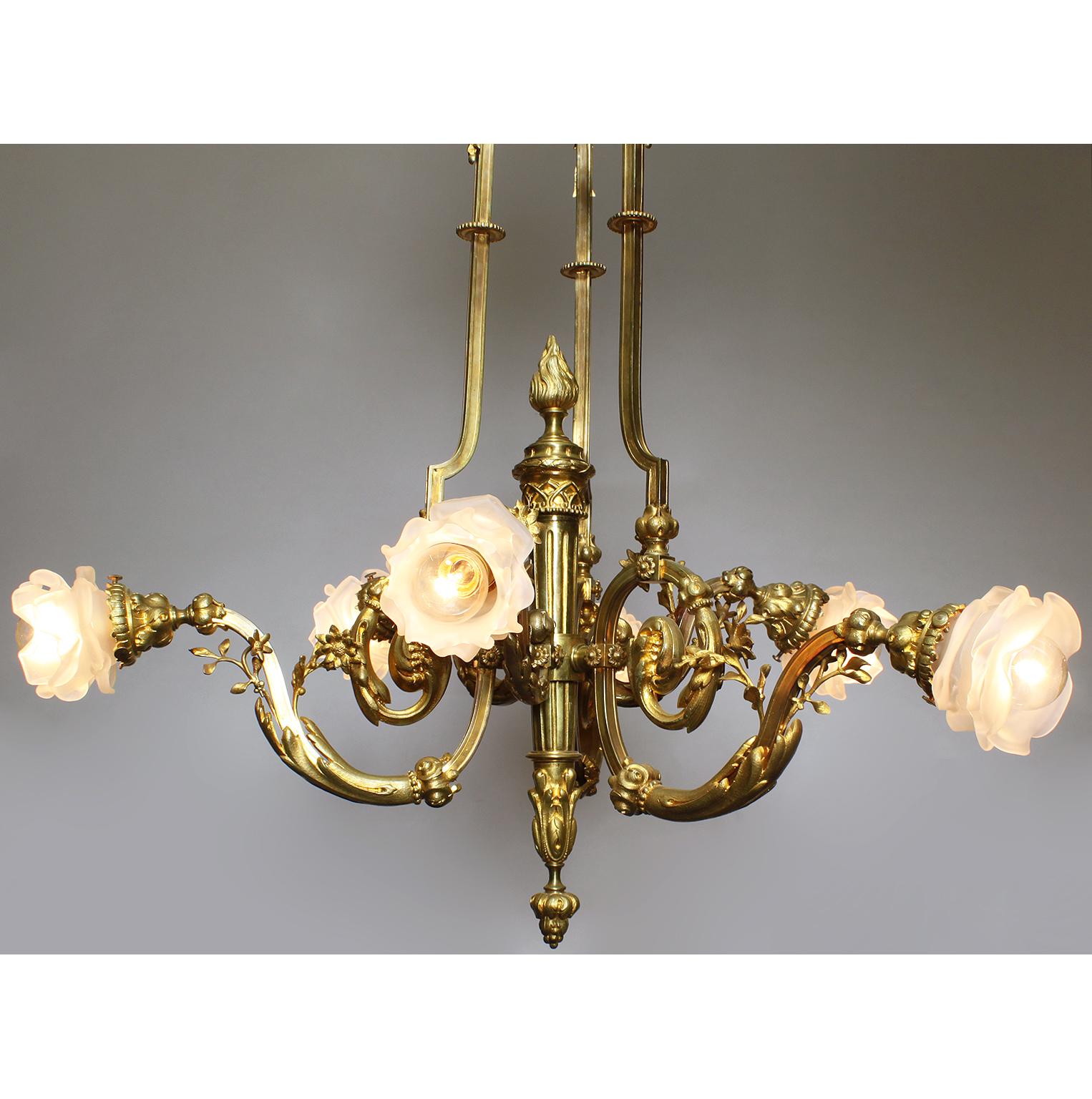 A fine French Louis XV style Belle Époque gilt bronze six-light chandelier. The Empire Revival gilt-bronze frame with a torch-shaped center stem with six scrolled arms fitted with frosted glass floral shaded, all crowned with a domed top surmounted