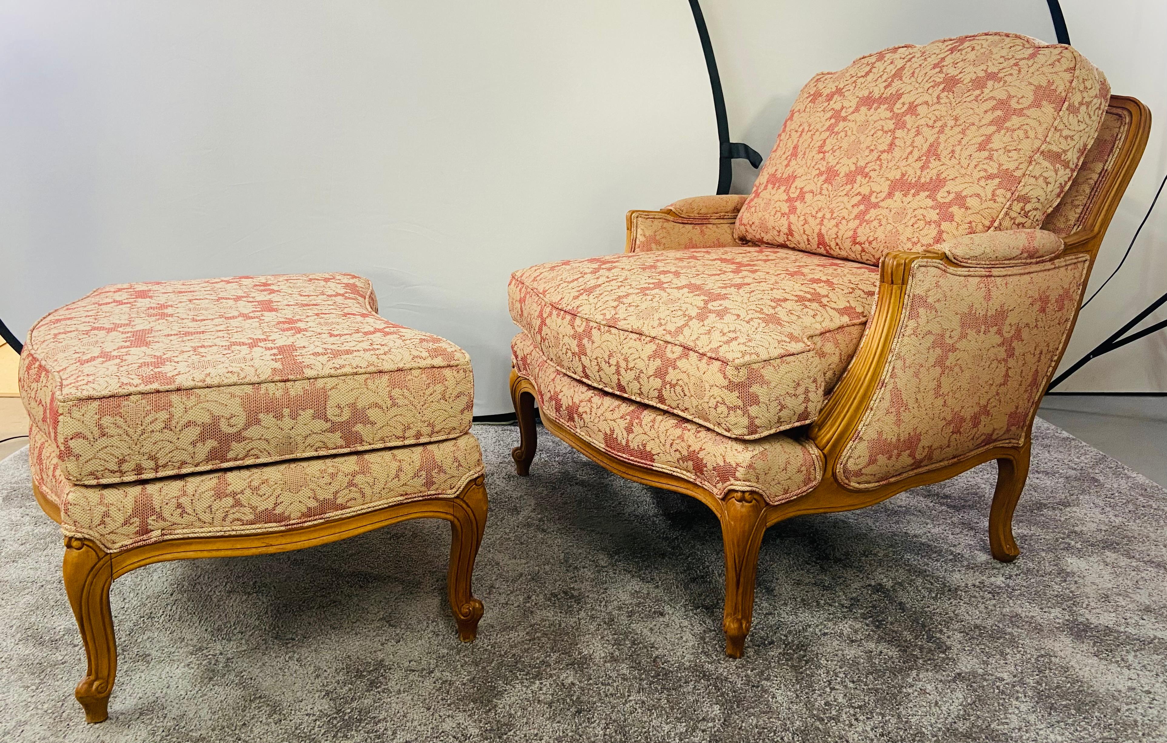 A French Louis XV Versaille style bergere chair or armchair by the Classic manufacturer / designer Ethan Allen. 
The comfortable bergere chair a double-welted back and seat cushion with a carved wood frame. Both the ottoman and the chair are nicely