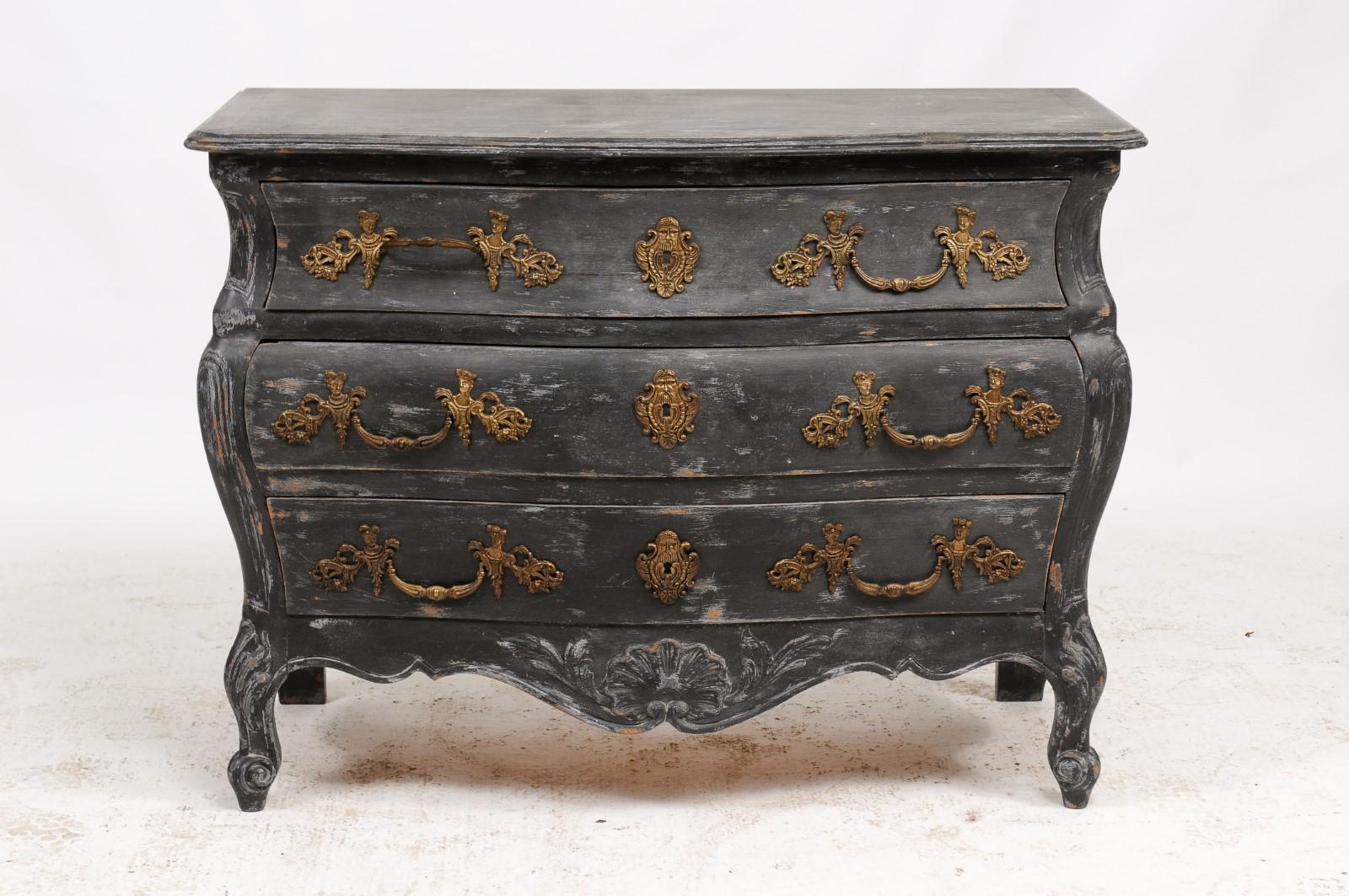 A French Louis XV style bombé three-drawer commode from the late 19th century, repainted in black, with Rococo style hardware, carved scalloped skirt and scrolled feet. This refinished, old, bombé-style commode caught our eye with its matte black